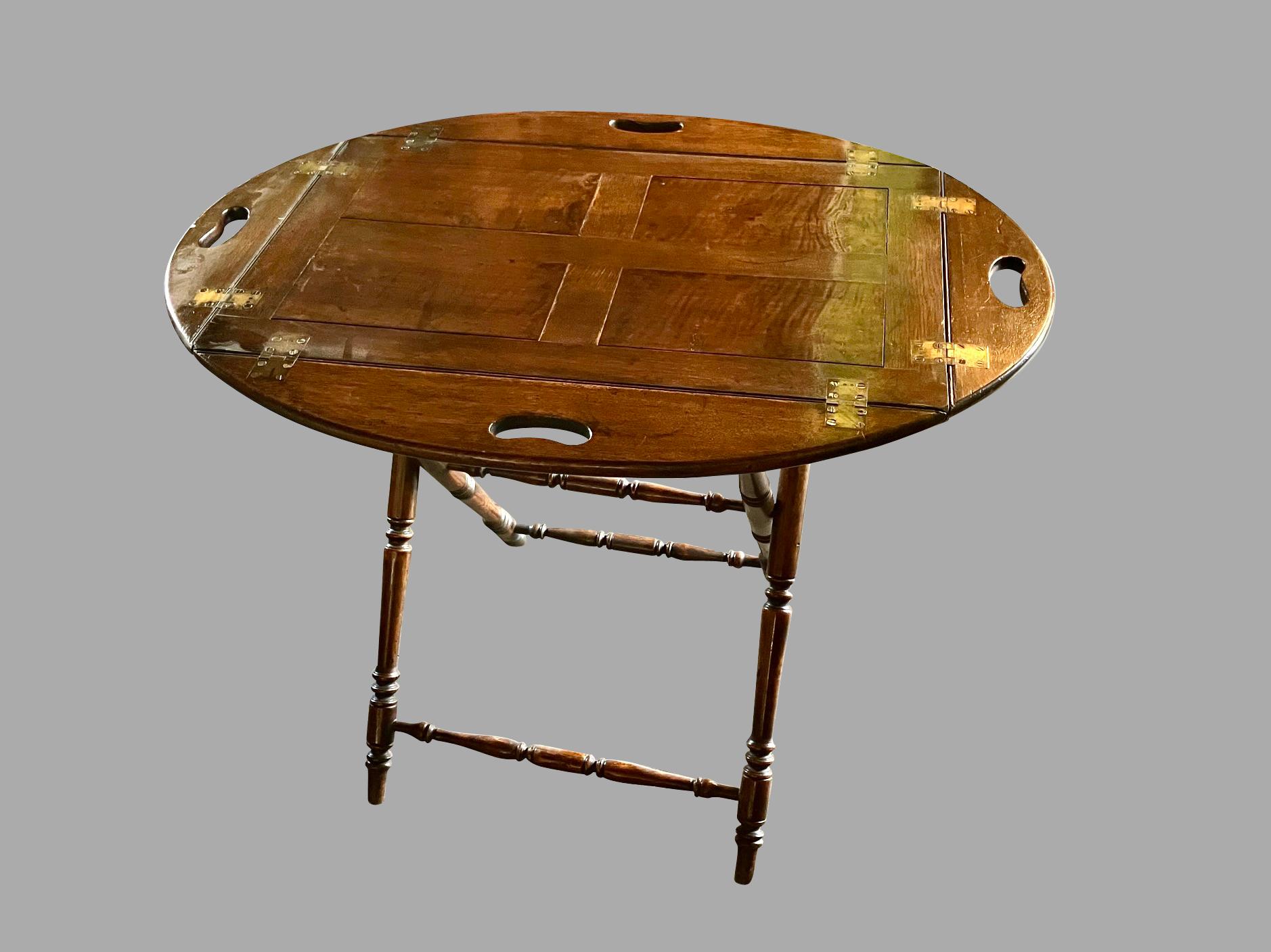 An English figured oak butler's tray with a paneled center, the collapsible sides with carry handles on each end. This attractive and useful tray rests on an associated folding mahogany stand. Nice color and patina. Makes a great portable bar.