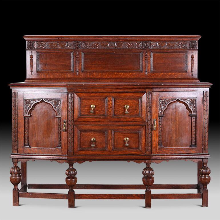 English solid oak sideboard with two drawers flanked by cabinets and with a carved panelled back. C.1920