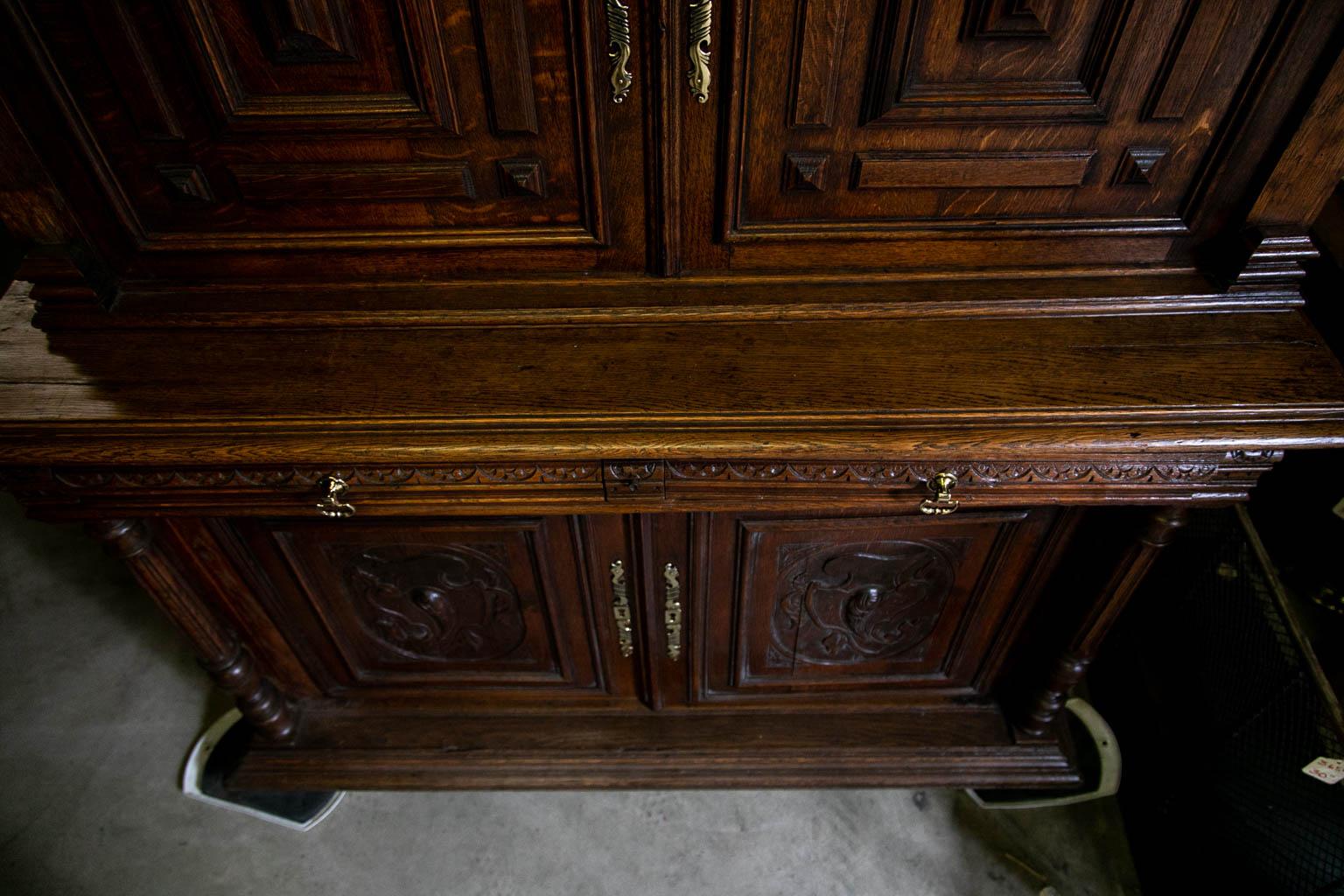 The doors in the upper section of this cupboard have applied carved moldings and panels. The lower doors have carved foliate cartouches framed by shaped moldings. The drawer fronts have repeating carved half-rosettes. The bottom section has fluted