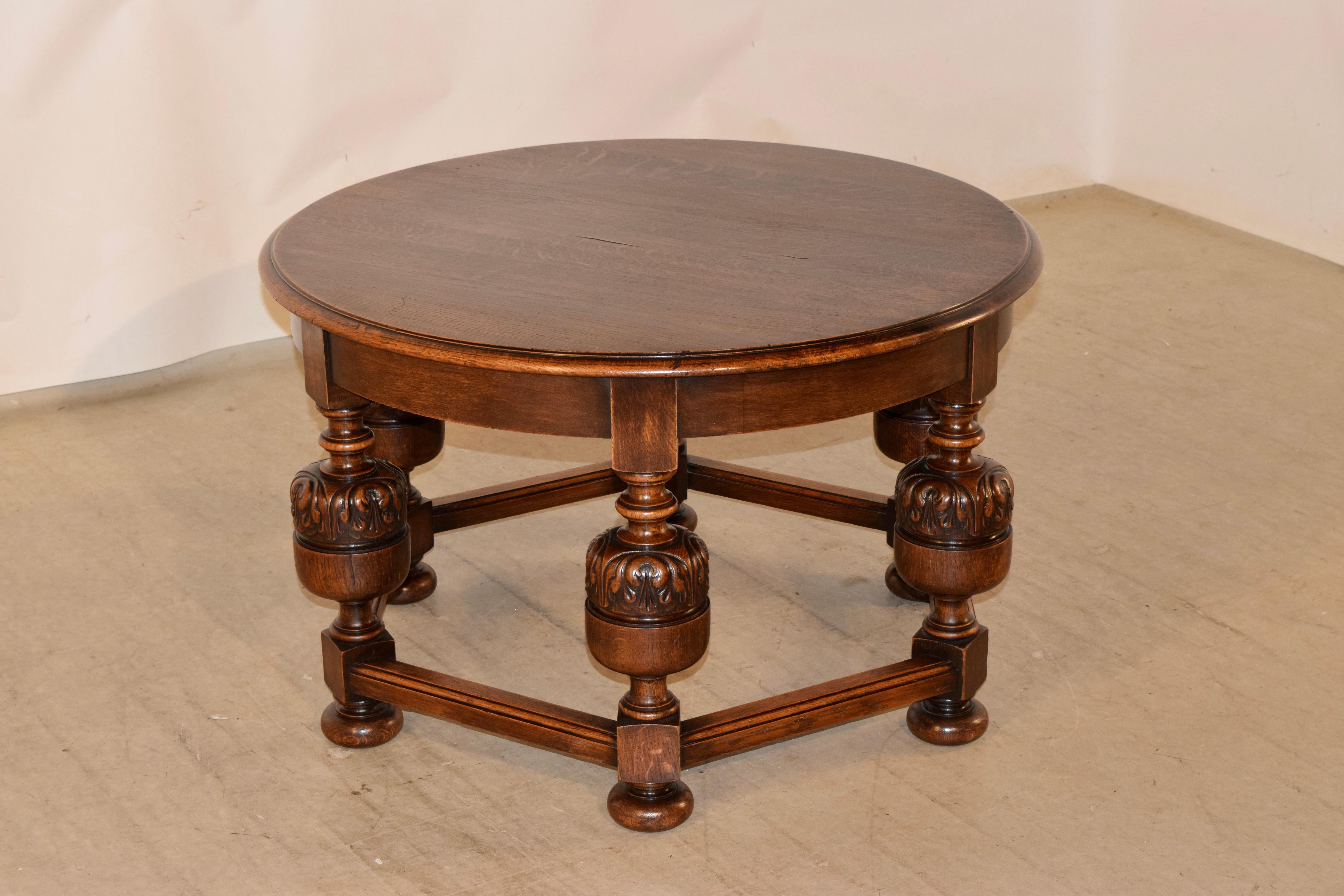 English oak cocktail table, circa 1900 with a wonderfully grained top in and a beveled and edge over thickly hand turned and carved decorated legs, joined by stout stretchers. Supported on hand turned bun feet.