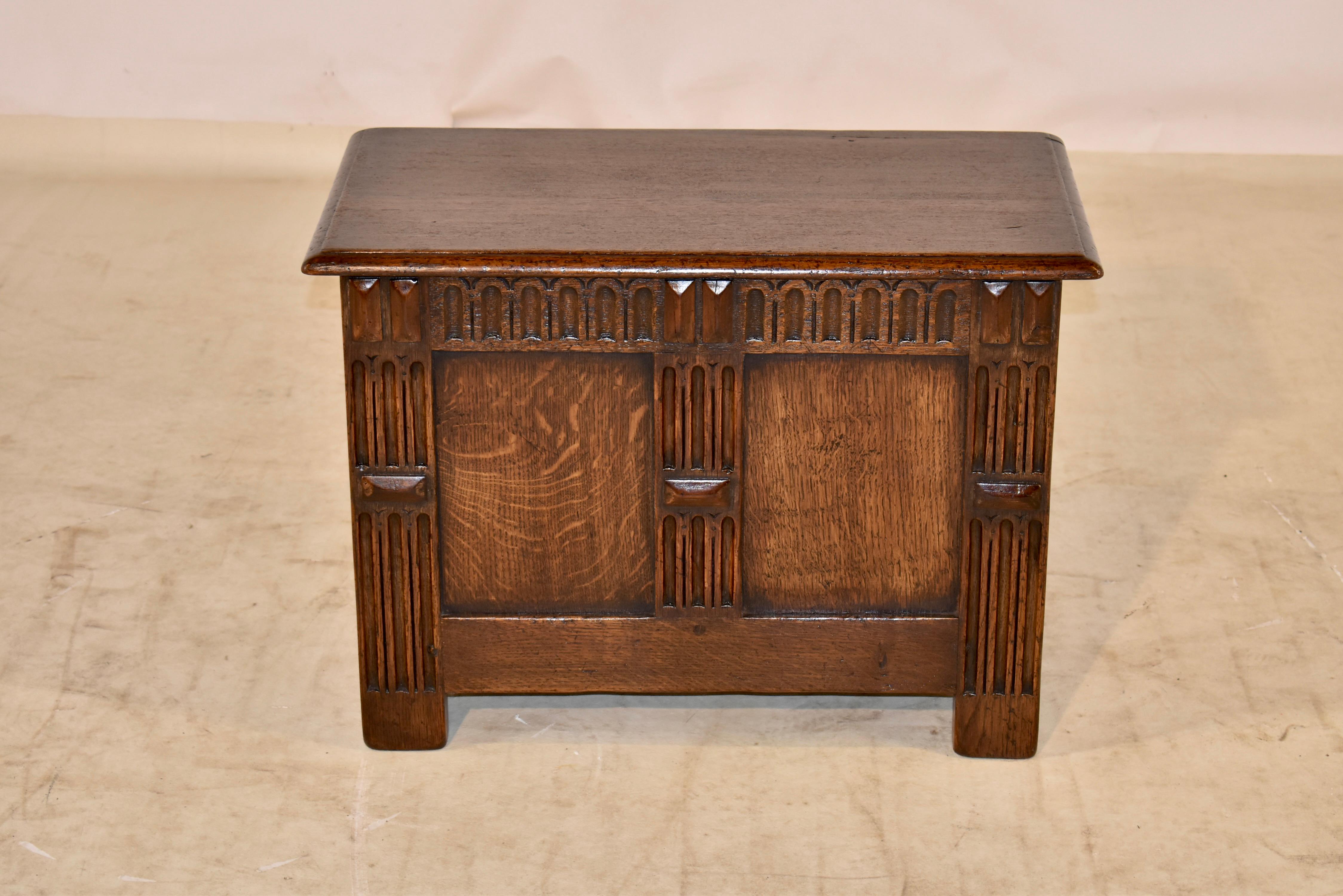 Period Edwardian oak small coffee from England with a lift top which has a lovely beveled edge, following down to simple sides and a paneled front and back.  The top lifts to reveal storage, and the piece is carved decorated in the front for added