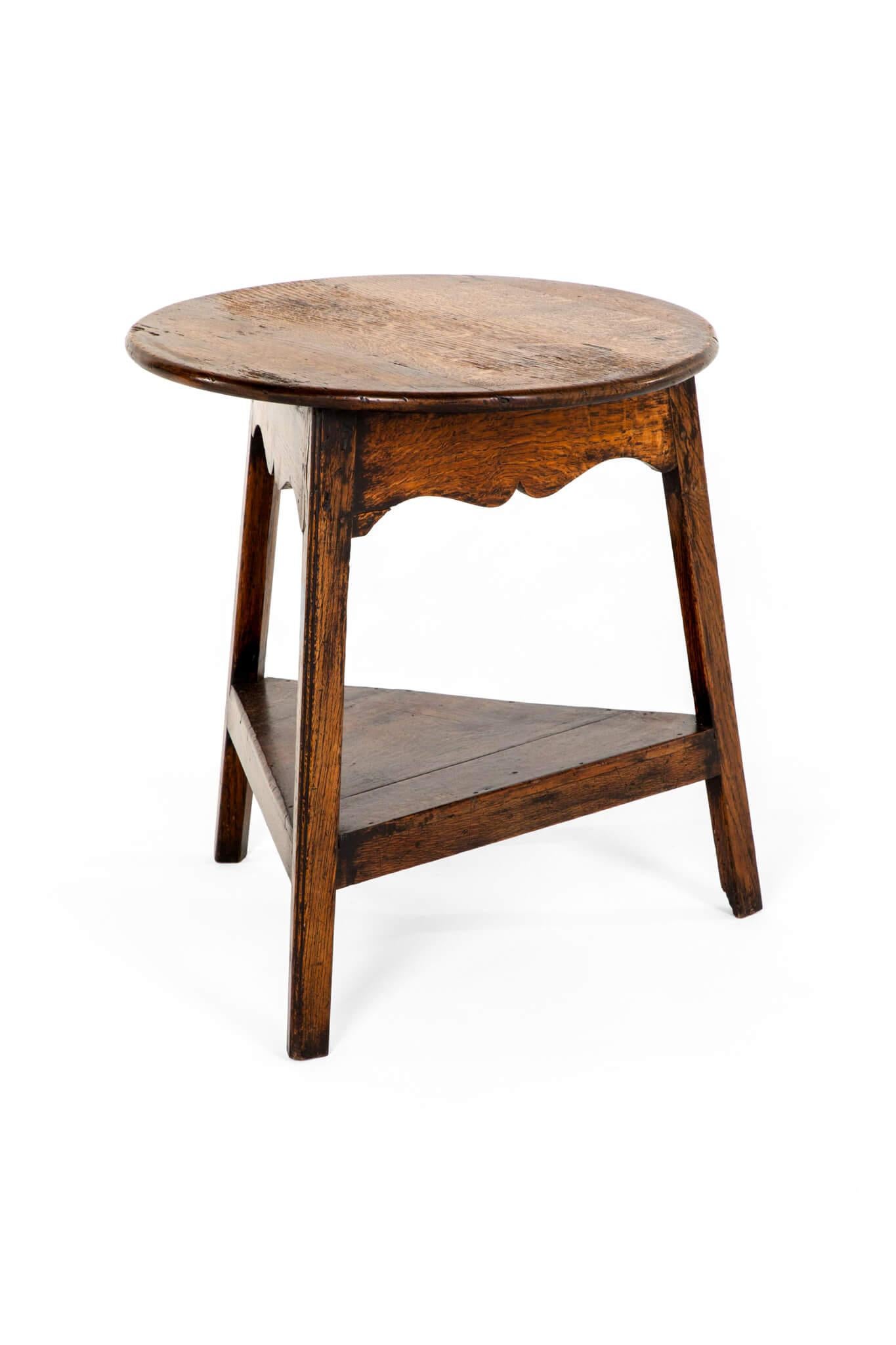 A mid-19th century English cricket table in oak with a wonderfully weathered patinated top.

Beneath a symmetrical waved frieze over a triangular tier base and raised on square section oak legs.

Exceptional colour and form throughout.

English,