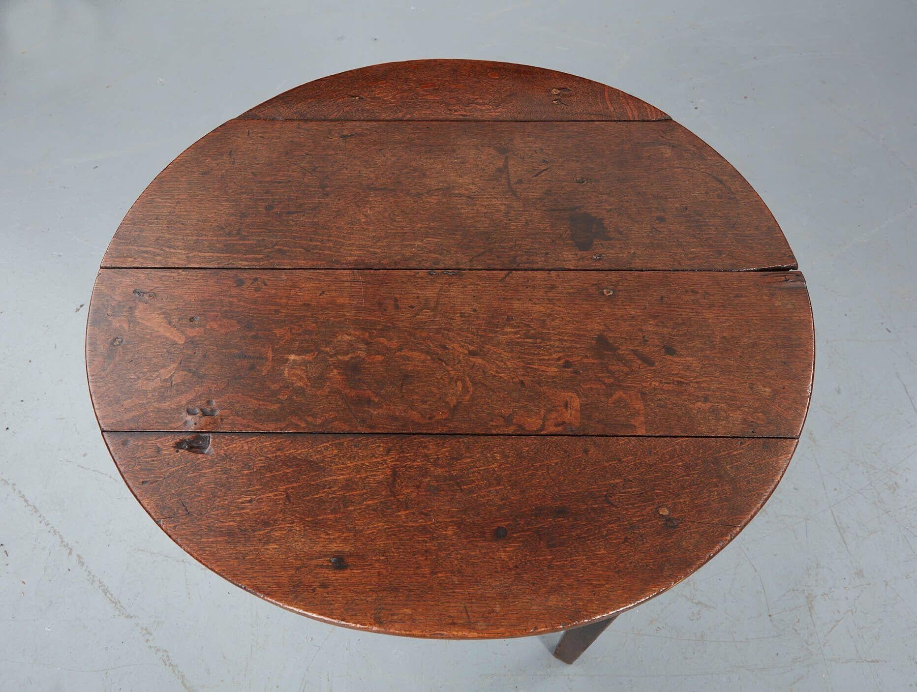 Oak four plank cricket table with eased apron over three quad section legs. Good size for two person dining or for use as a lamp table next to a sofa. Country house condition - some splits and chips.