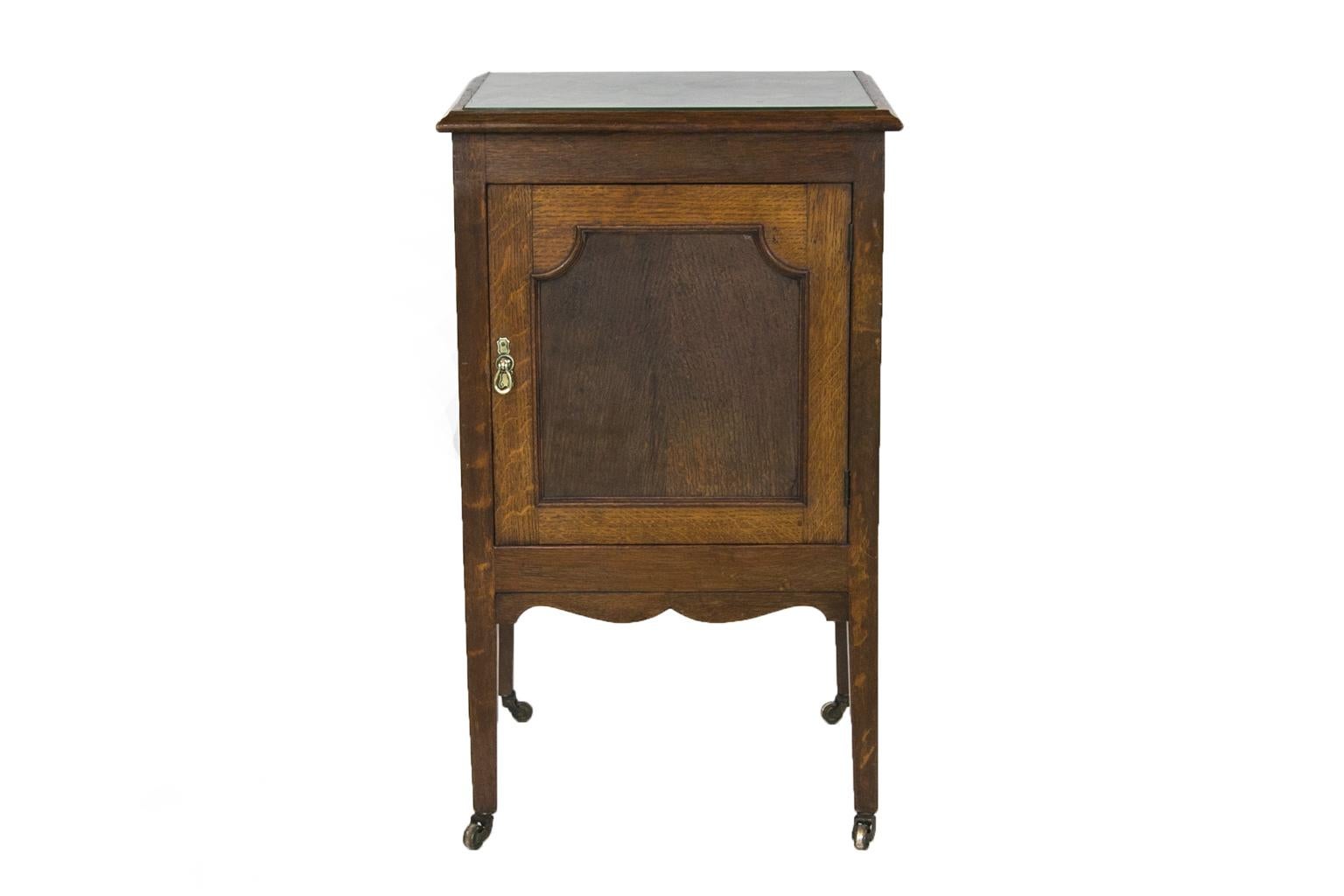 This cupboard has a top that has an inset panel covered with a floral fabric protected by a glass top, which is later. It has an ogee molded frame. The door has a recessed panel framed by a shaped molding. The sides also have recessed panels. The