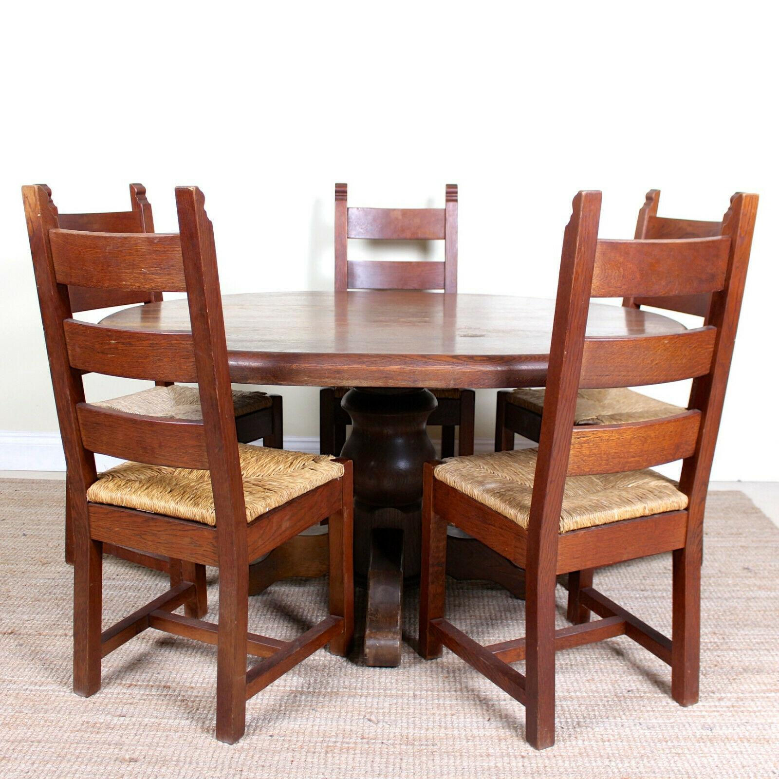 An impressive antique six-piece oak dining suite.
Constructed from thick cuts of oak boasting a well figured grain.
The dining chairs constructed from solid oak with rushwork seats.
The dining table with an oval top raised on a bulbous column and