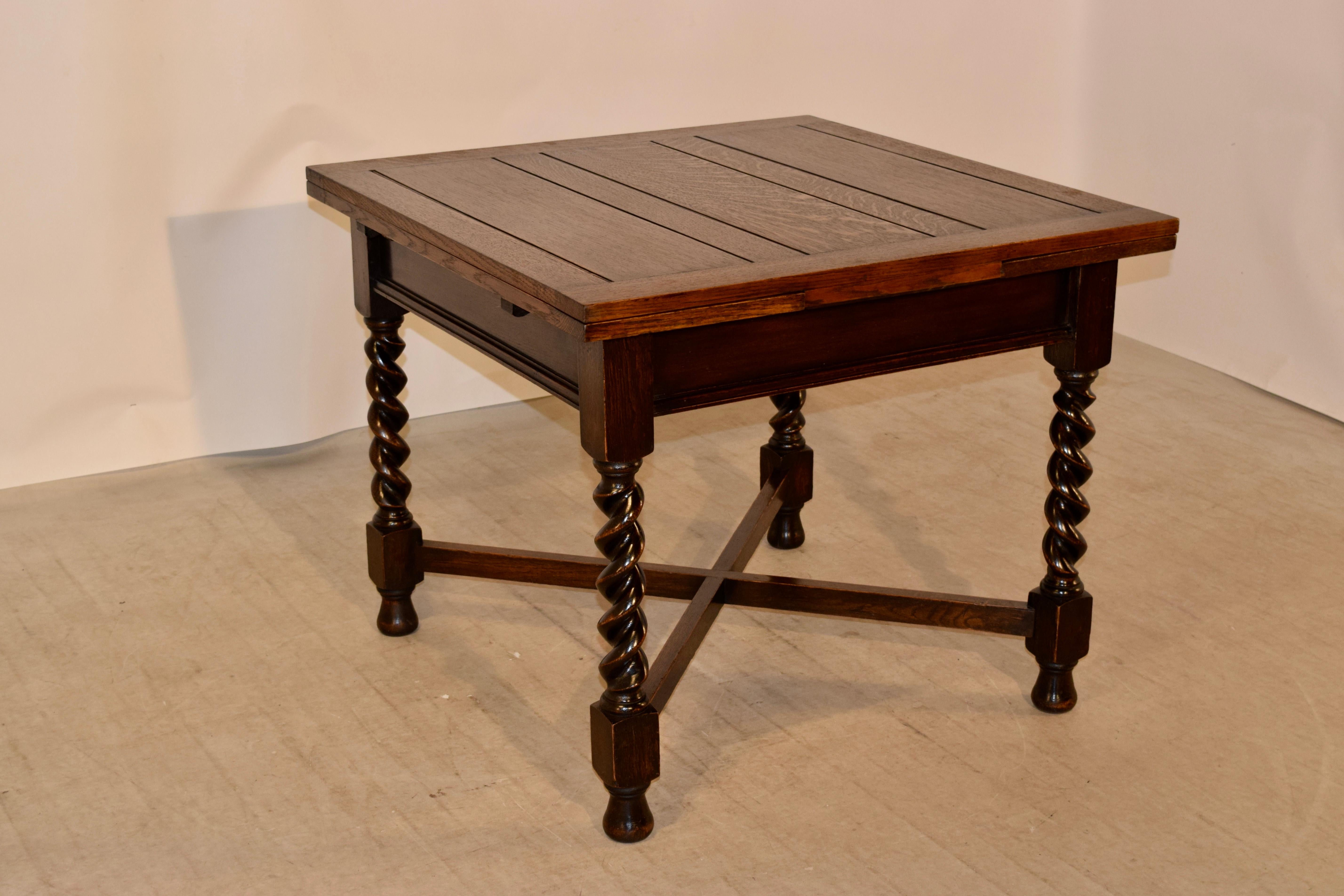 English oak table with draw leaves, circa 1900. The top and leaves are both paneled and follow down to a simple apron with a molded edge and supported on hand-turned barley twist legs joined by cross stretchers and raised on hand-turned feet. The