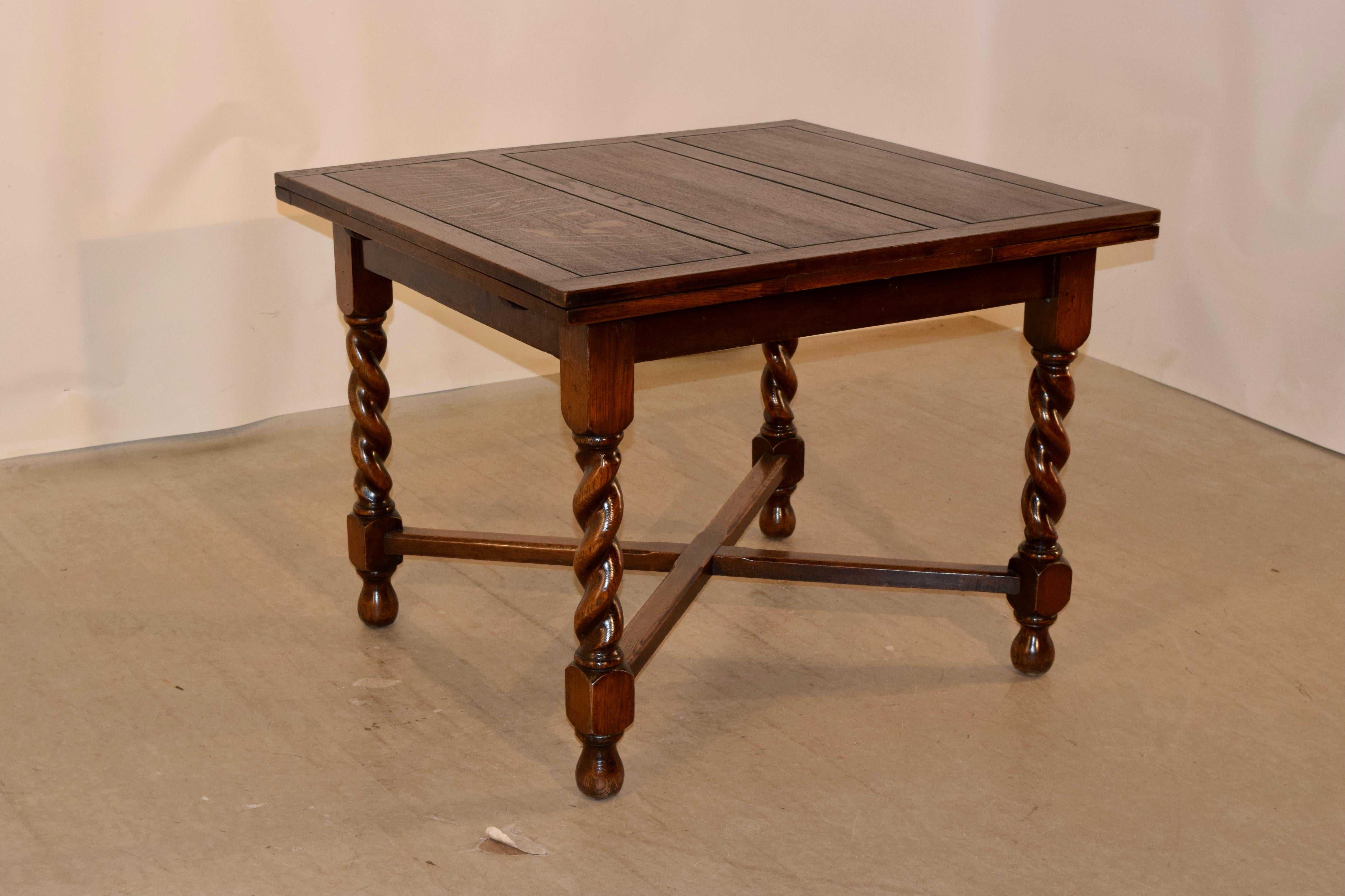 English oak table with two draw-leaves circa 1900. The table has a nicely paneled top and leaves over a simple apron and supported on hand-turned barley twist legs, which are joined by simple cross stretchers and raised on hand-turned bun feet. The