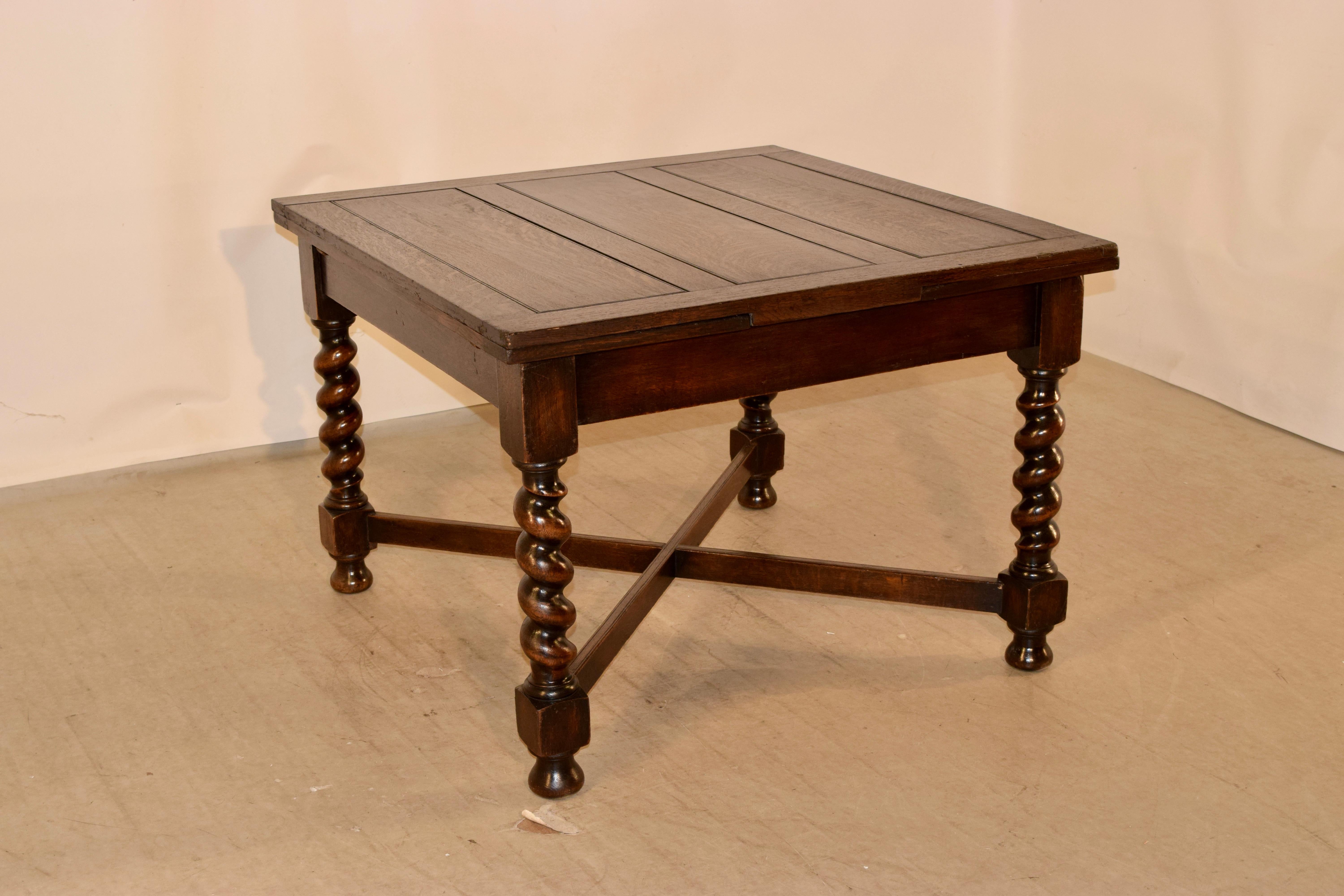 English oak table with two draw-leaves circa 1900. The table has a nicely paneled top and leaves over a simple apron and supported on hand-turned barley twist legs, which are joined by simple cross stretchers and raised on hand-turned bun feet. The