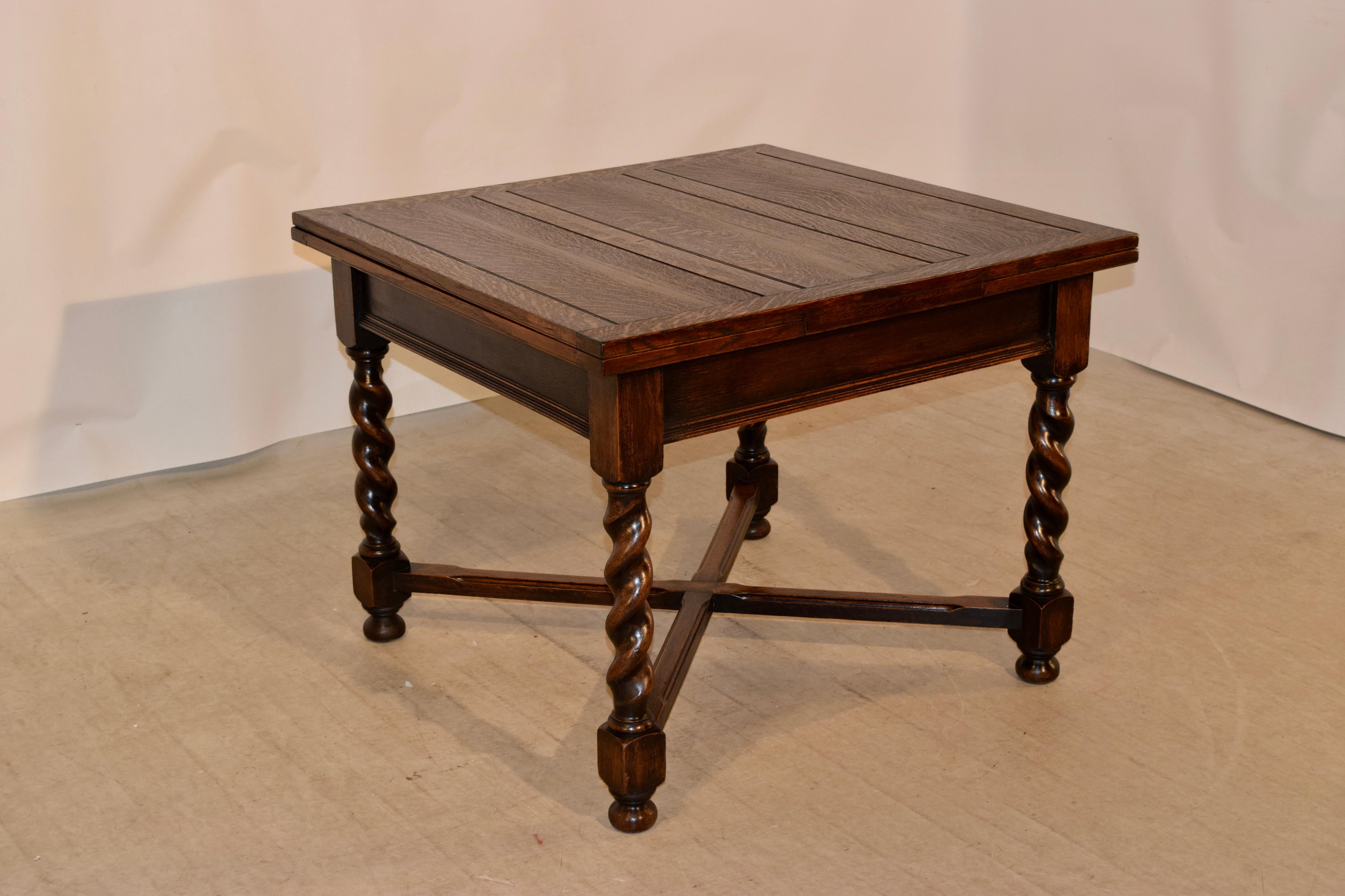 English oak table with draw leaves, circa 1900. The top and pull out leaves are paneled, and are supported on a base with a simple apron which has a molded edge following down to hand turned thick barley twist legs, joined by simple cross stretchers
