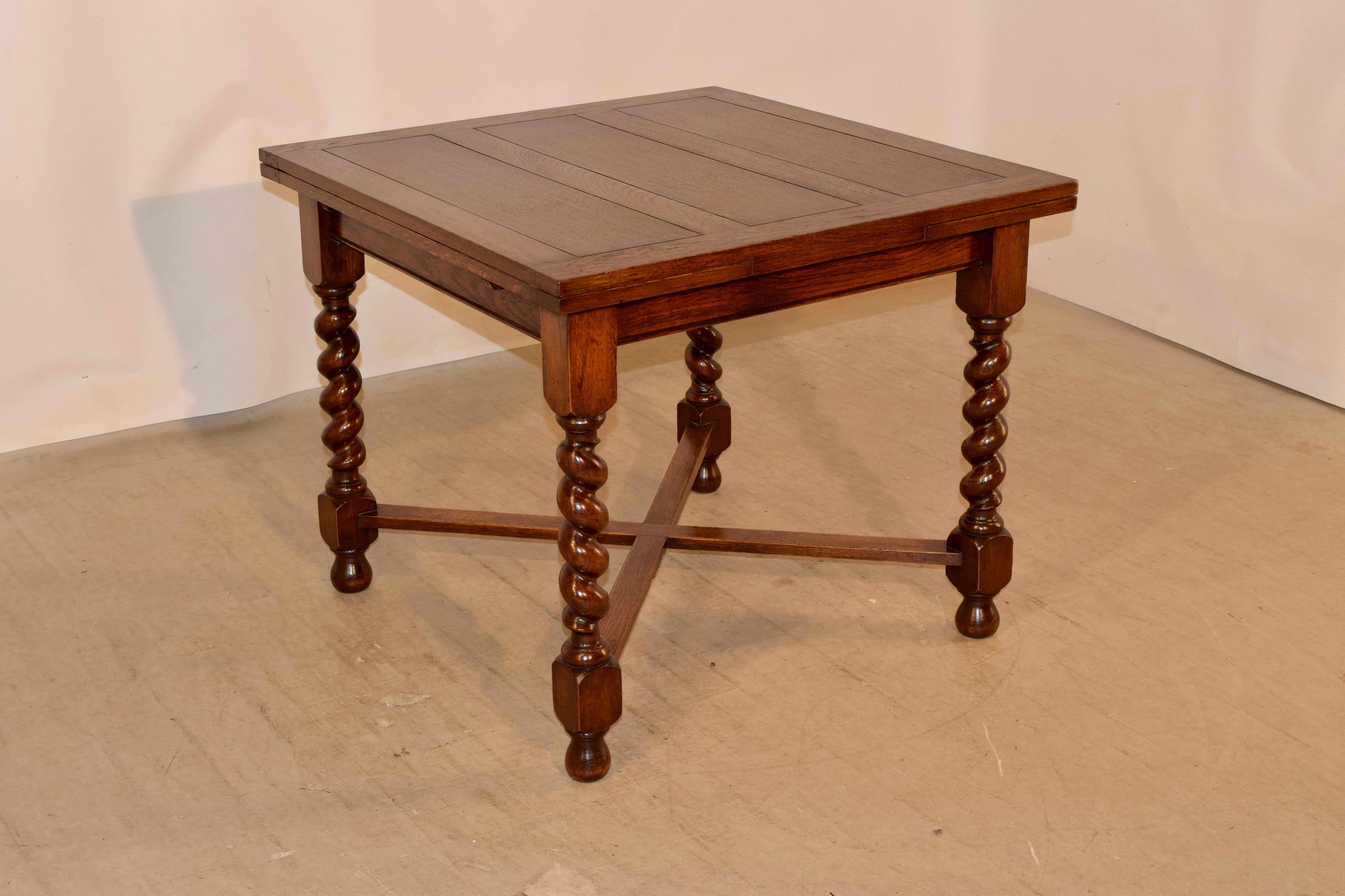 English oak table with draw leaves, circa 1900. The top and pull out leaves are paneled, and are supported on a base with a simple apron which has a molded edge following down to hand turned thick barley twist legs, joined by simple cross stretchers