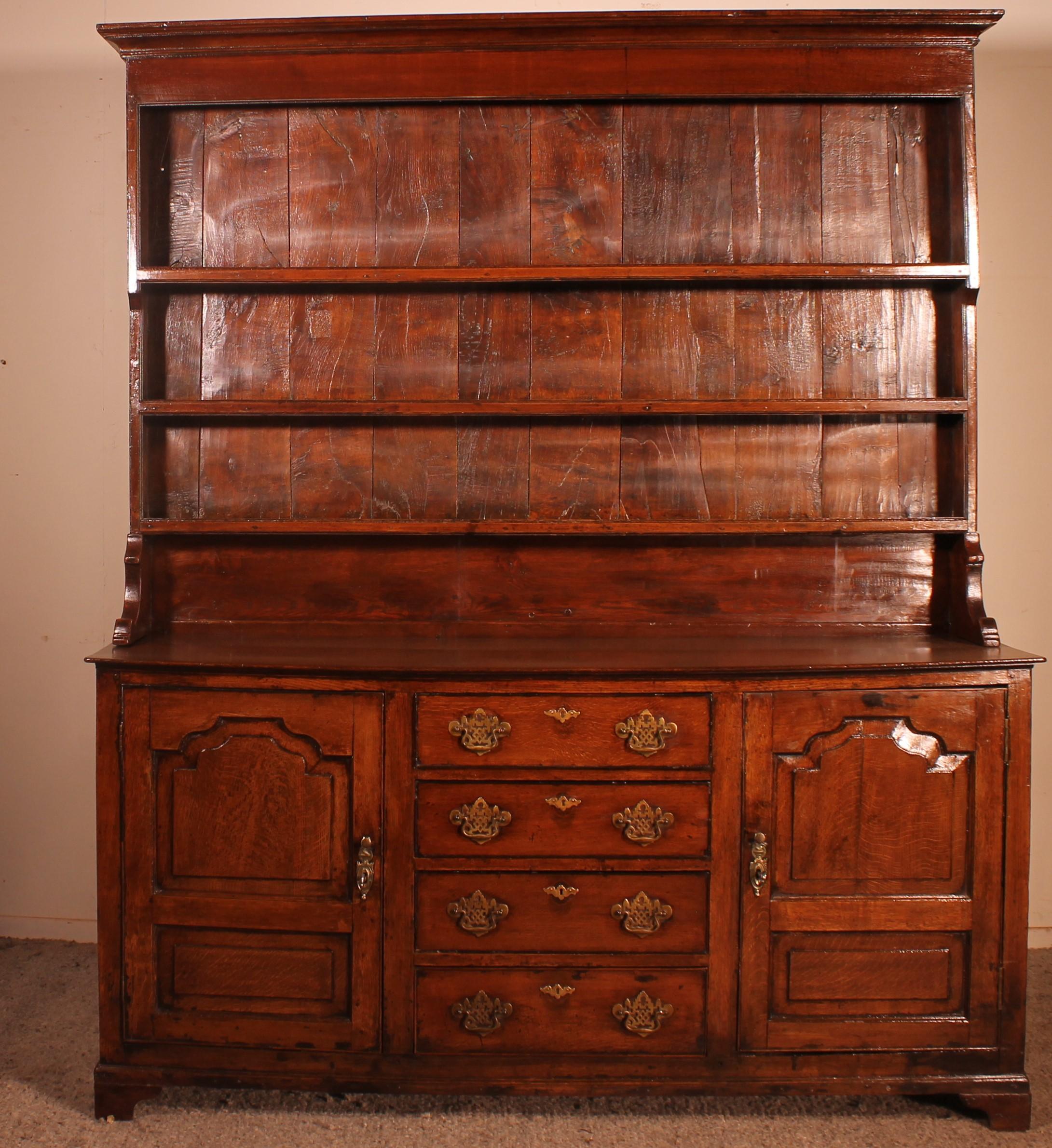 Superb English dresser from the beginning of the 18th century in oak
Very nice model with very beautiful molded doors. We can find a symmetry in the two doors. This indicates that it is from the beginning of the 18th century.

The bottom of the