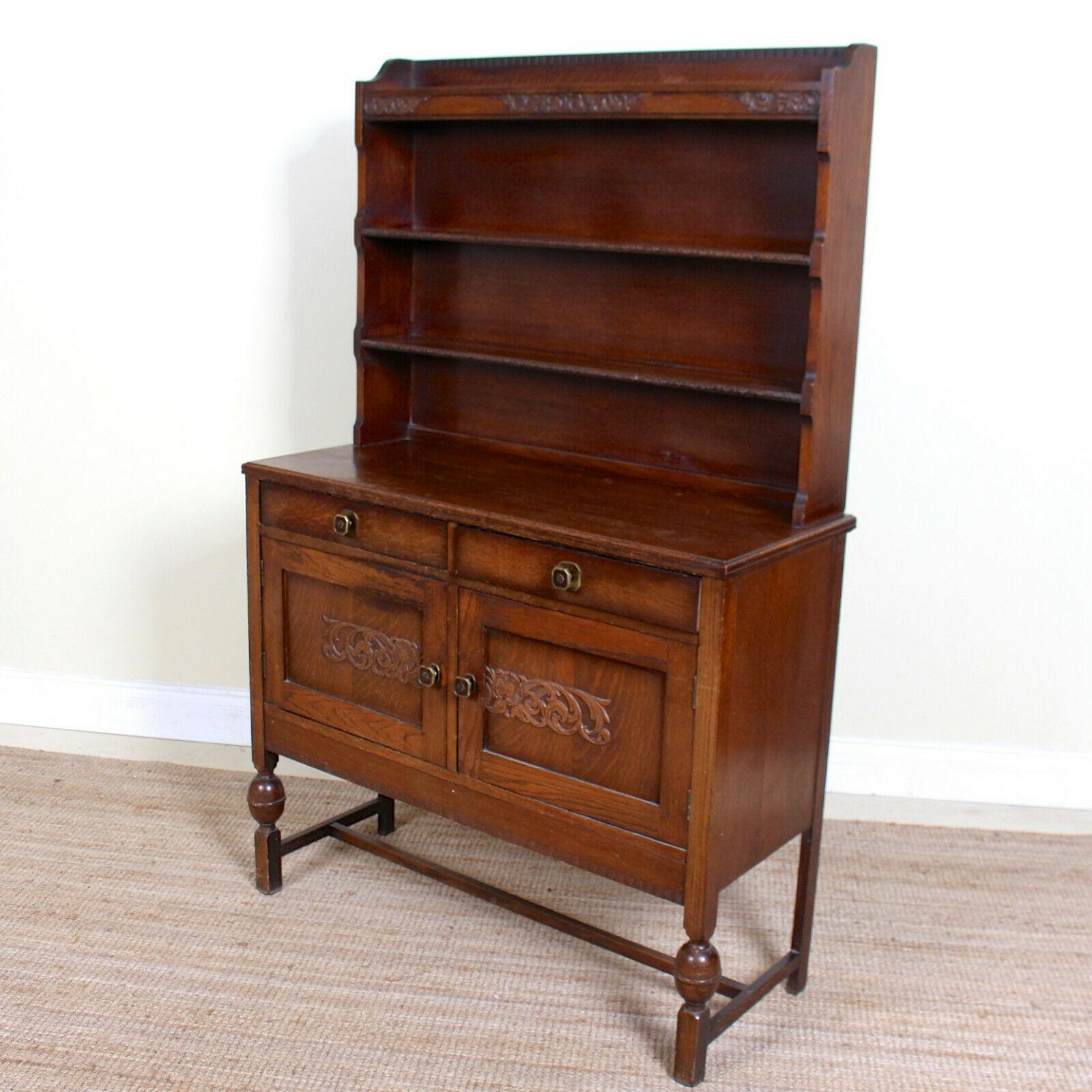An impressive oak dresser in the Arts & Crafts manner.

The oak boasting a well figured grain.

The upper section with carved frieze and shelving. The lower section fitted two drawers above carved paneled doors enclosed storage and raised on