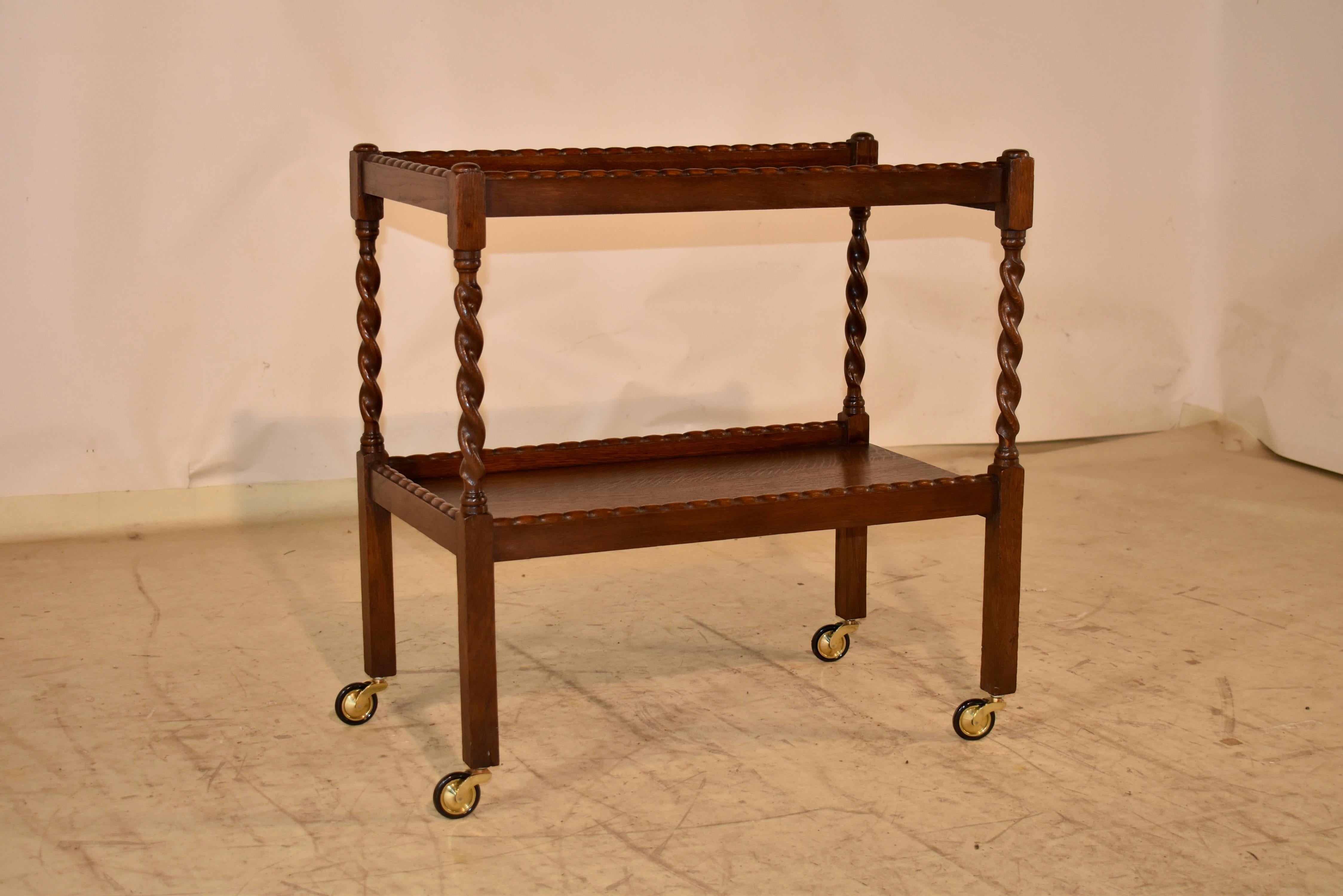 Carrello per bevande in rovere inglese di epoca edoardiana del 1900 circa.  Il carrello è dotato di due ripiani, entrambi con gallerie che presentano deliziose bordature decorative lungo i bordi superiori per aggiungere interesse al design.  Le