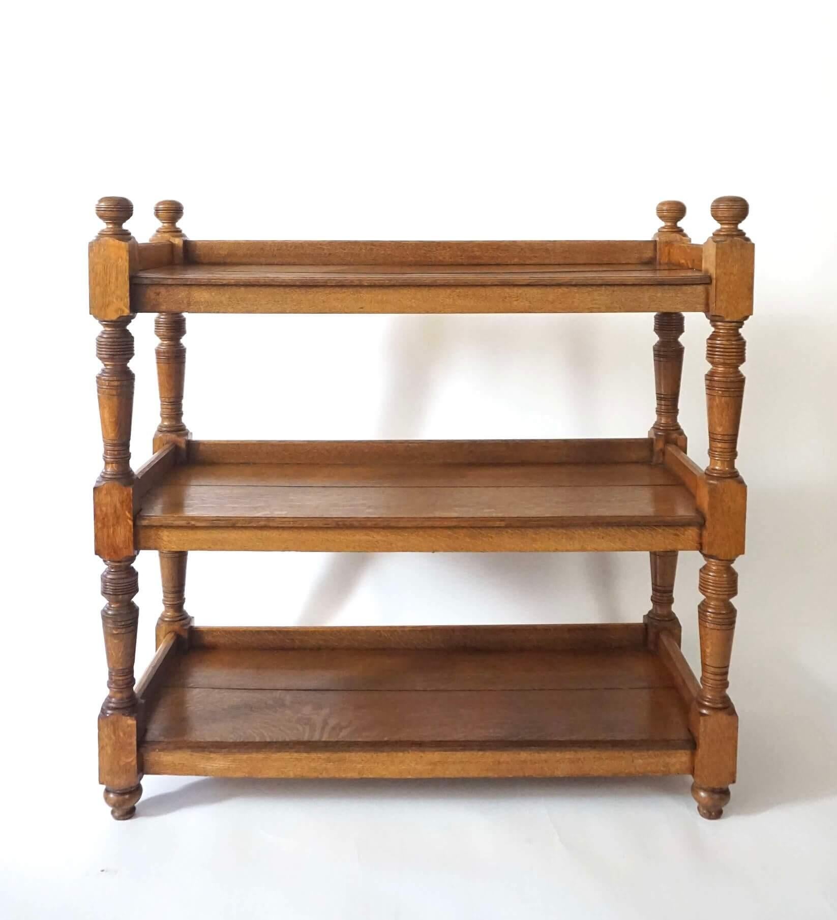 Servidor, carro de alambiques, etagere o estantería abierta de roble macizo inglés de hacia 1875, de forma rectangular de tres pisos, con remates de bolas torneadas y montantes en las esquinas que sostienen estanterías de dos tablones con galerías.