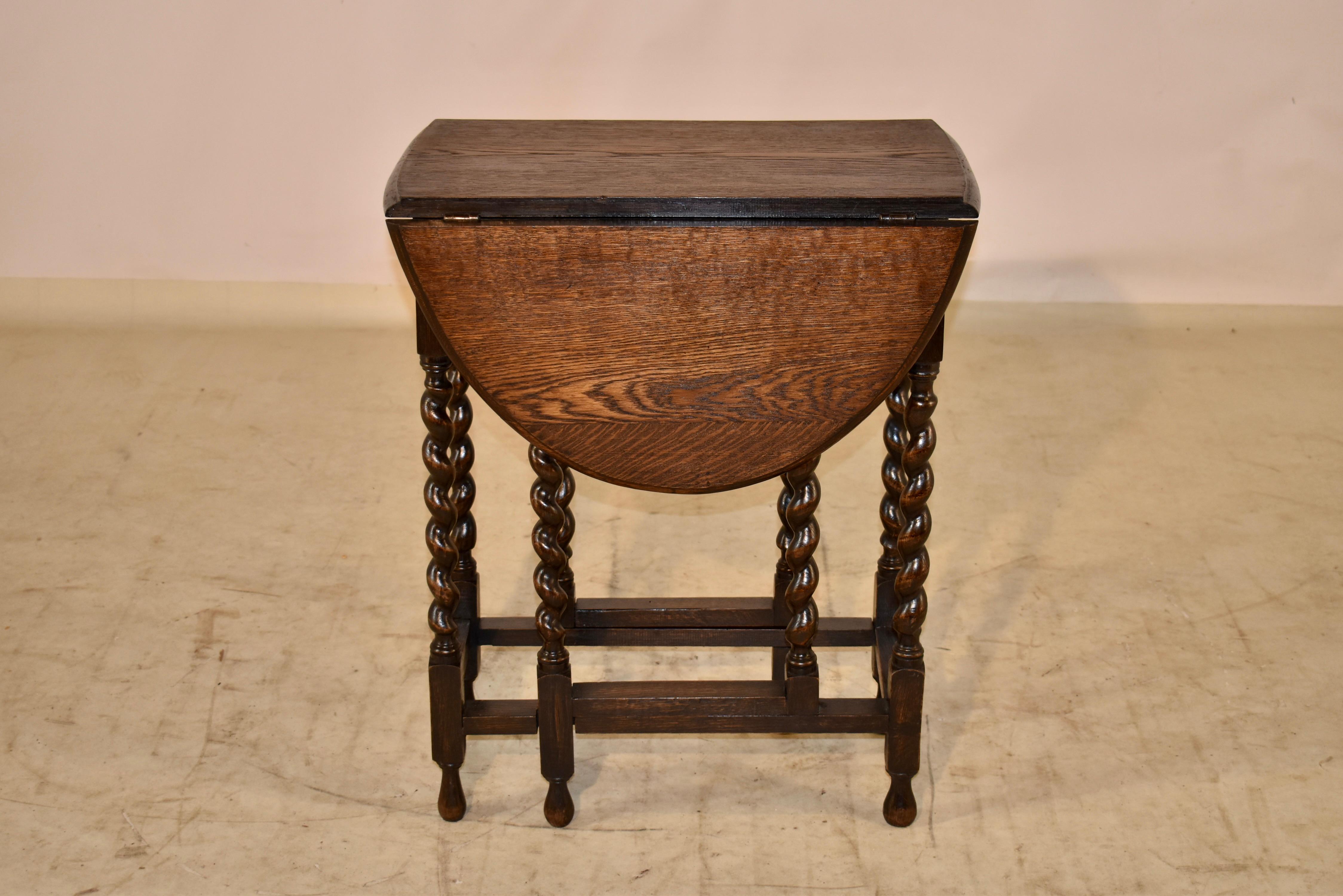 Circa 1900 oak gate leg table from England with a beveled edge around the top, following down to a simple apron and supported on hand turned barley twist legs, joined by simple stretchers. The top measures 35 inches x 23.5 inches when open.