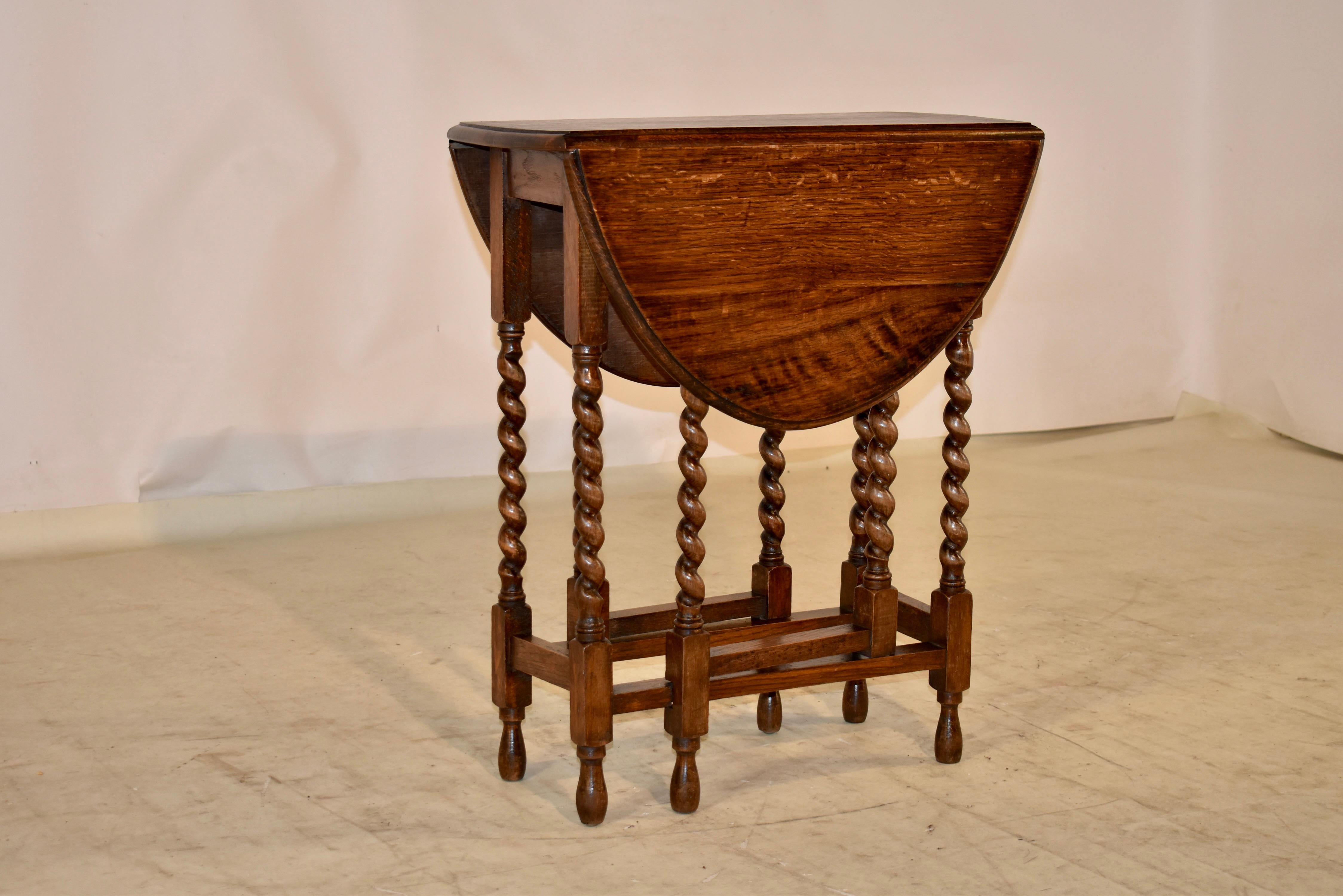 Edwardian oak gate leg table, c. 1900. The table has a beveled edge around the top, following down to a simple apron. The table is supported on hand turned barley twist legs, joined by simple stretchers and raised on hand turned feet. The table top