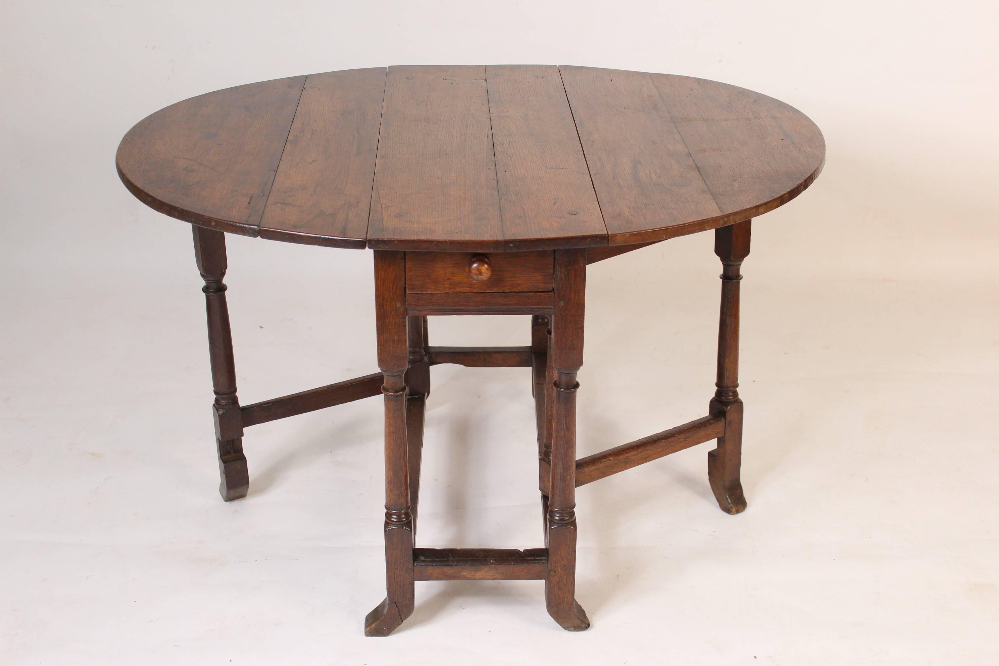 Antique English oak gate table, 19th century. This table has excellent old color, pegged construction and hand dove tailed drawers. The measurements of the top when the drop leafs are up, width 44