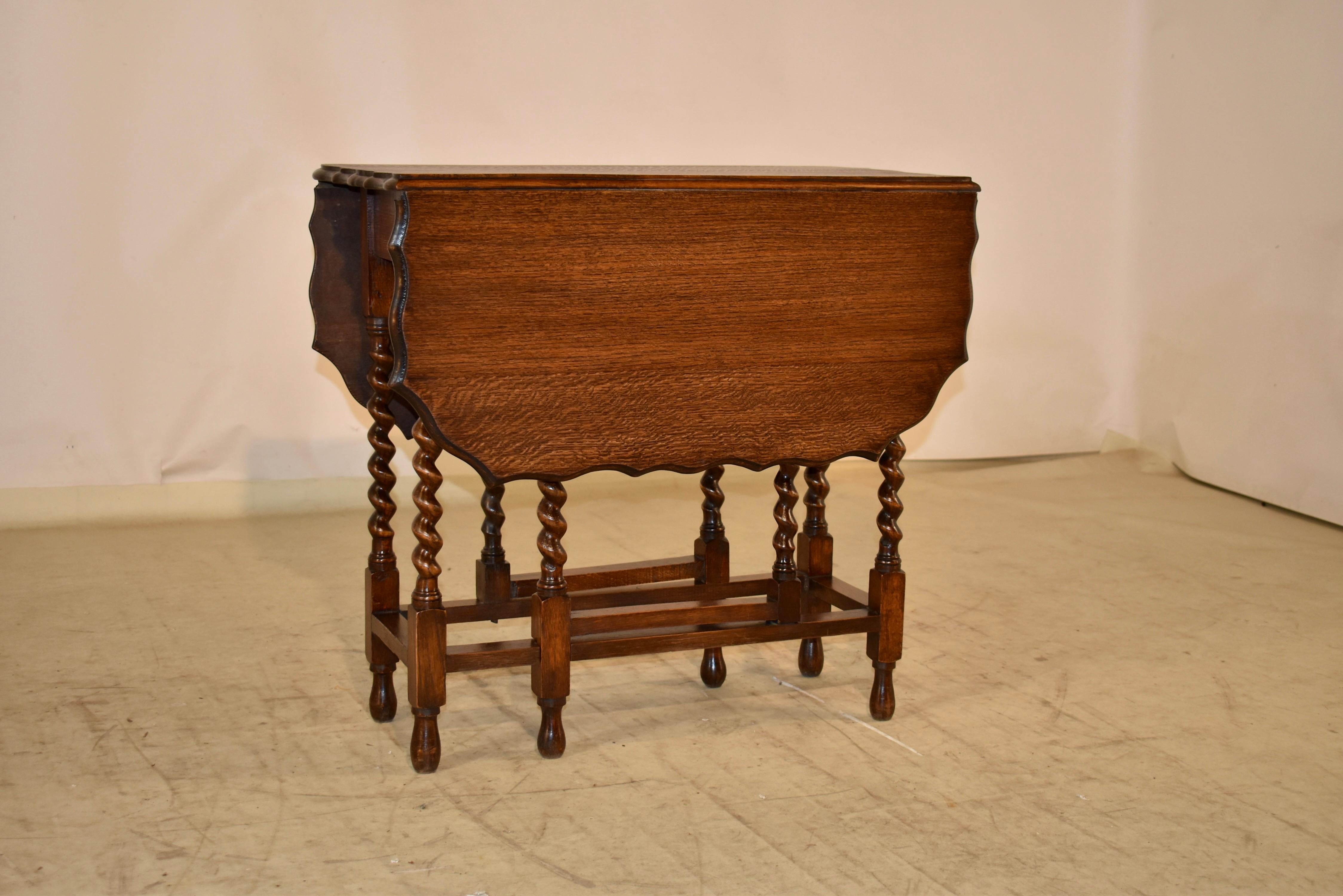 Period Edwardian oak gate leg table from England.  The top has a lovely beveled and scalloped edge, following down to a simple apron and hand turned barely twist legs on the table and gates.  The legs are joined by simple stretchers and are