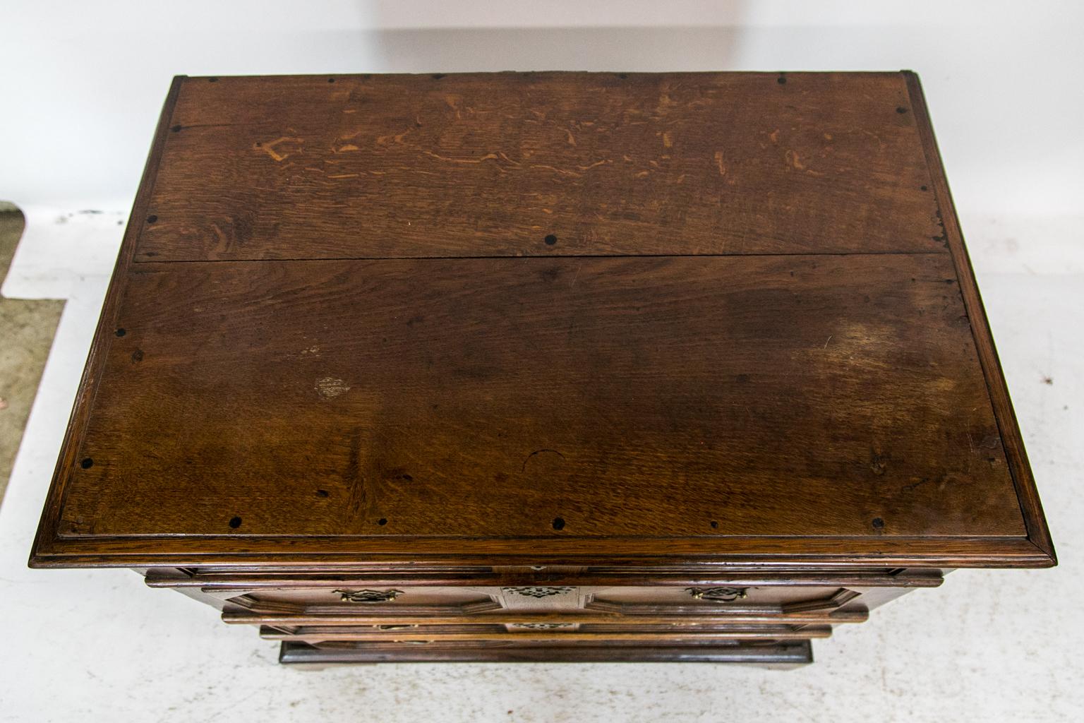 The drawers of this oak geometric chest have two recessed panels in each drawer framed with shaped moldings in rectangular and geometric shapes. The top drawer has a secret lock accessed by opening the second drawer and depressing a wooden