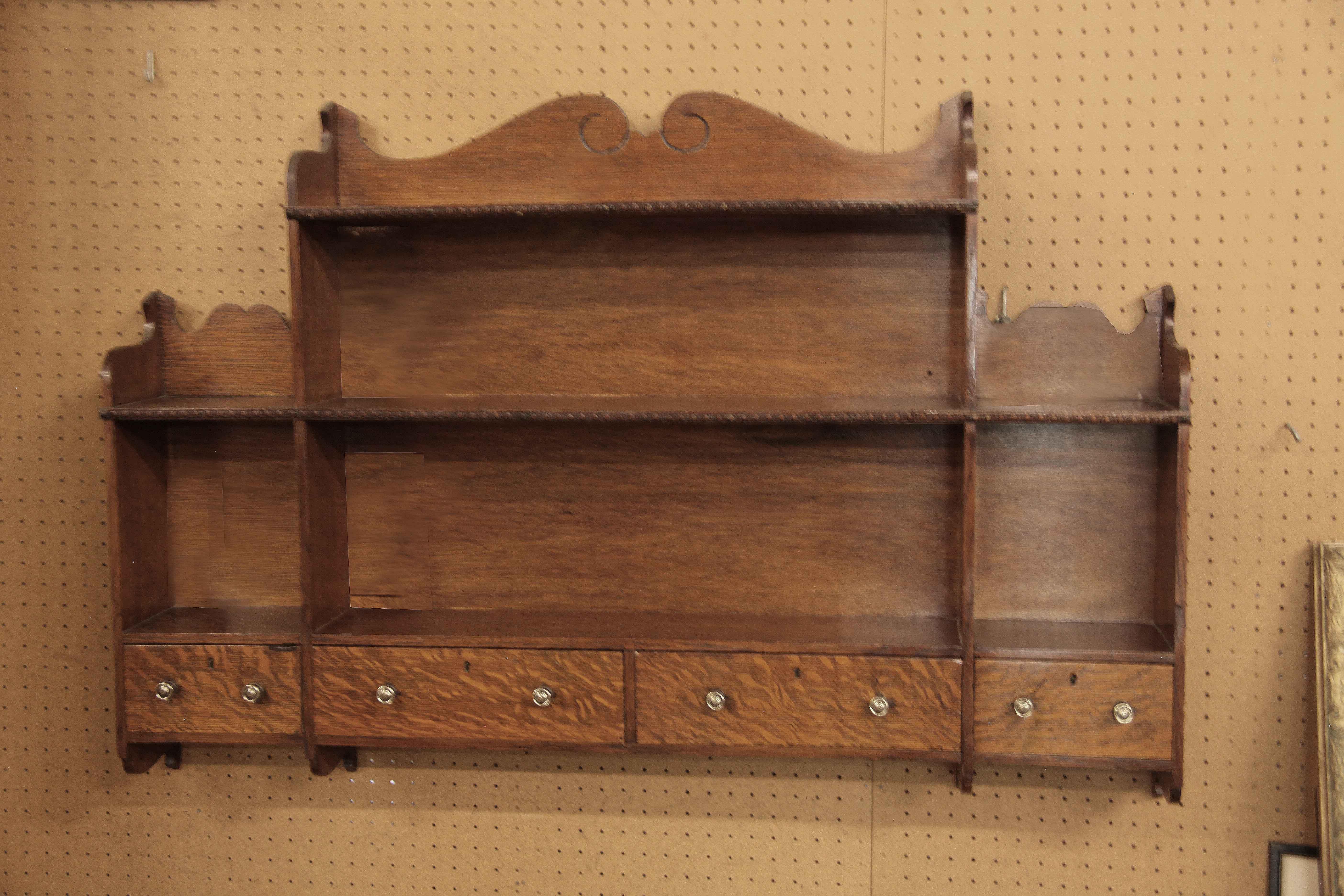 English oak hanging shelf,  the center top section with serpentine shape,  the shelves in the center and each end have clearance of 9.5'' (bottom shelf) and 8'' for the one above.  The four drawers feature beautiful quarter sawn oak and brass knobs.