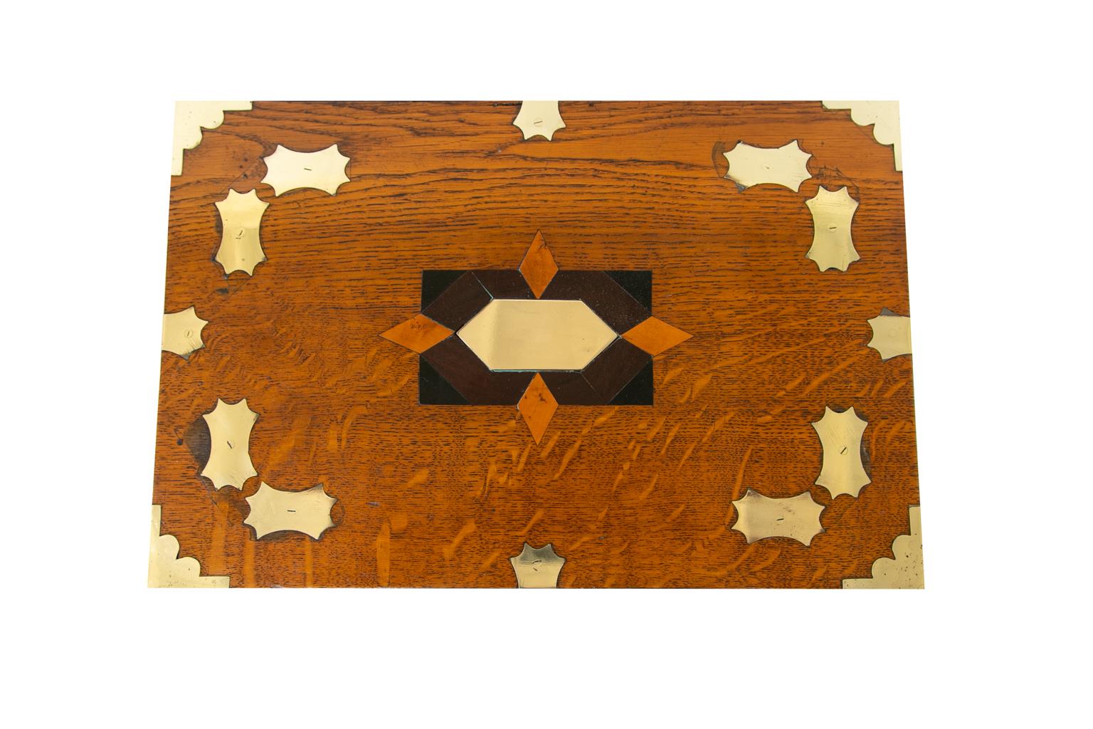 English oak inlaid writing box, is elaborately inlaid with shaped brass panels and corner bindings. The top also has a panel inlaid with ebony, boxwood, and mahogany. The interior has fitted compartments and trays.
          