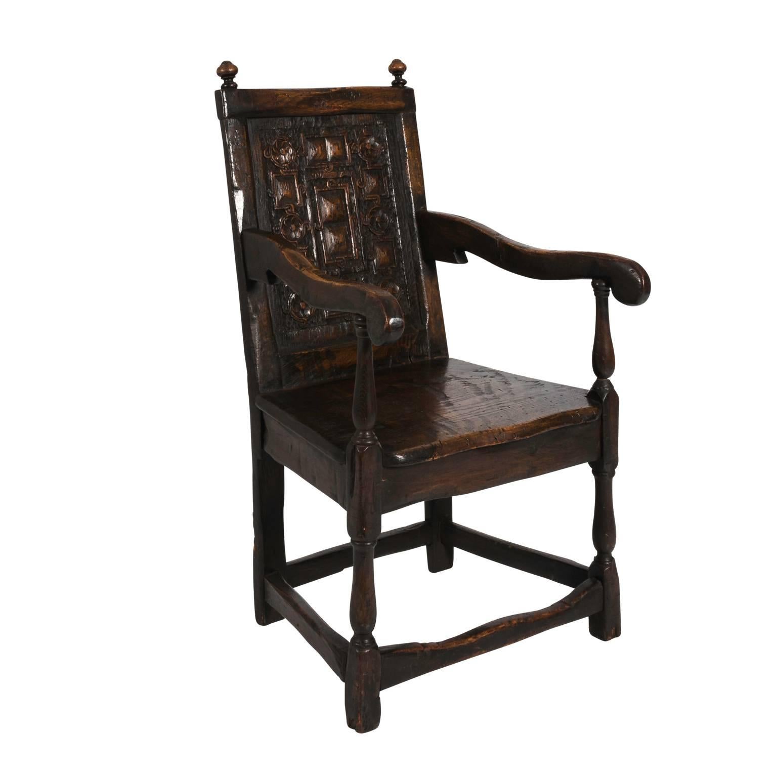 English Oak Jacobean style arm chair with heavy relief carvings on the back and a box stretcher, circa late 19th century.
 