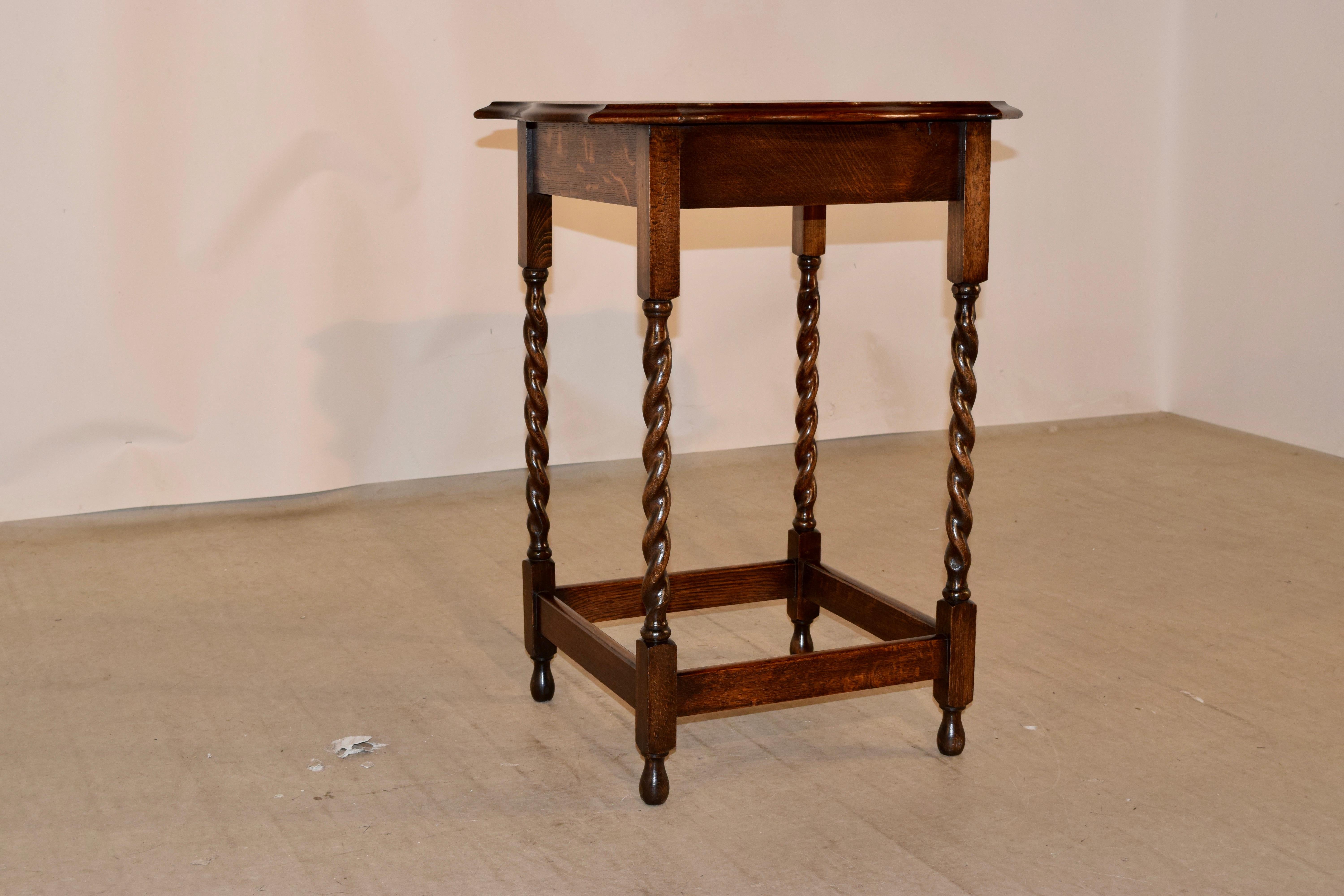 English occasional table, circa 1900 made from oak. The top is scalloped and has a beveled edge, following down to a simple apron and supported on hand-turned barley twist legs, joined by stretchers and raised on turned feet.