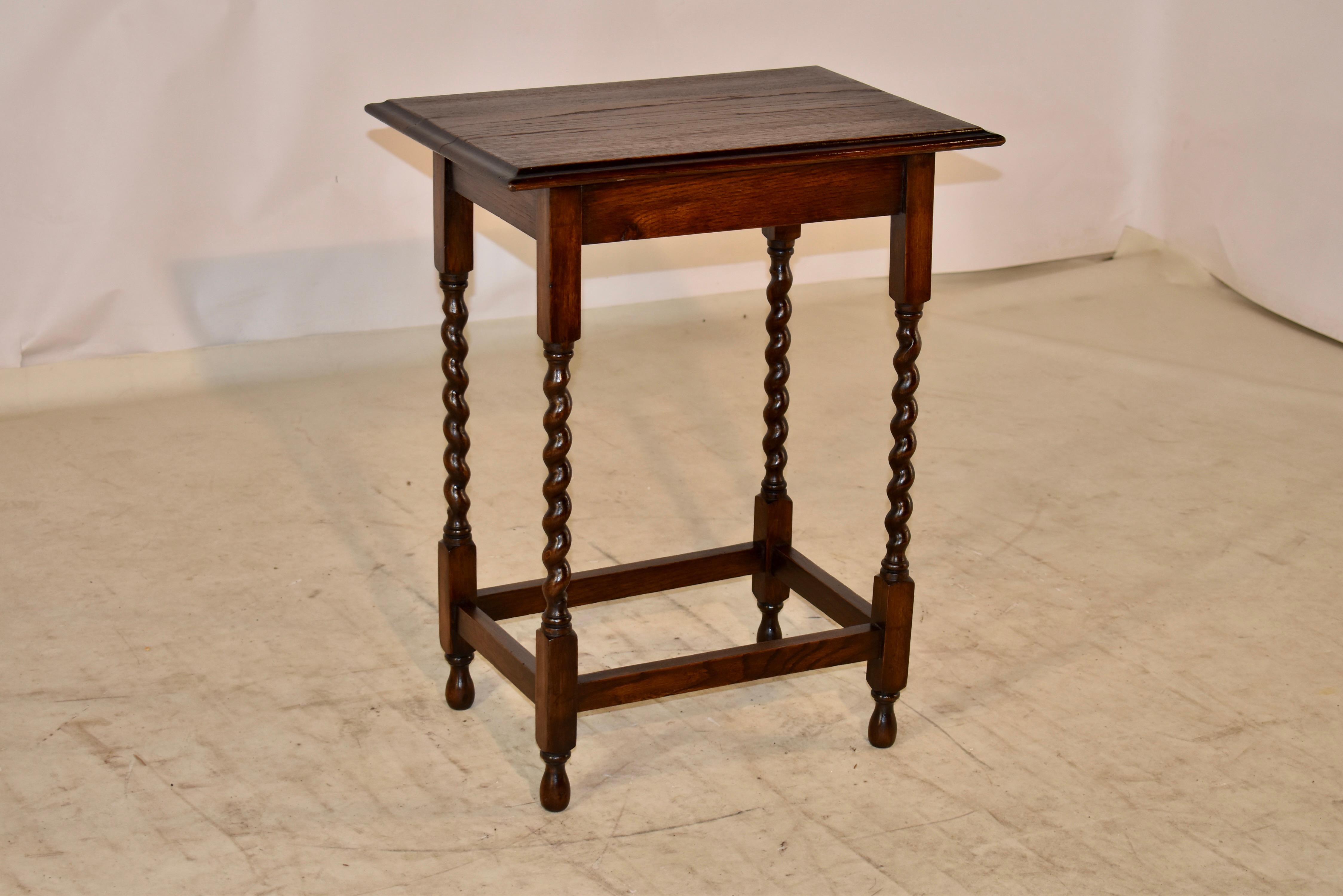 Circa 1900 Edwardian English oak side table with a beveled edge around the top, following down to a simple apron and supported on hand turned barley twist legs, joined by simple stretchers.