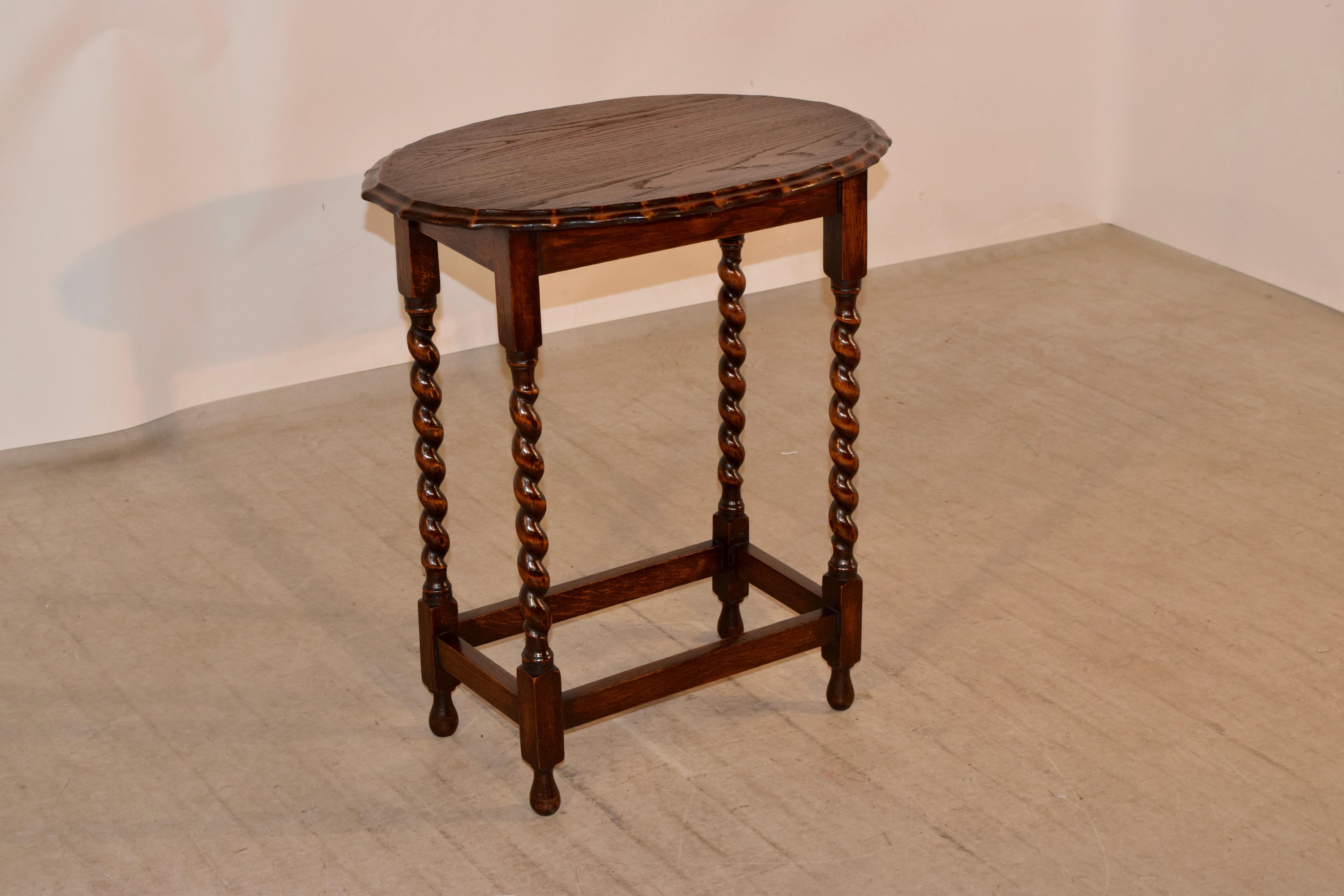 English oak occasional table with a scalloped and beveled edge around the top, following down to simple aprons and supported on hand-turned barley twist legs, joined by simple stretchers and raised on hand-turned tulip shaped feet.