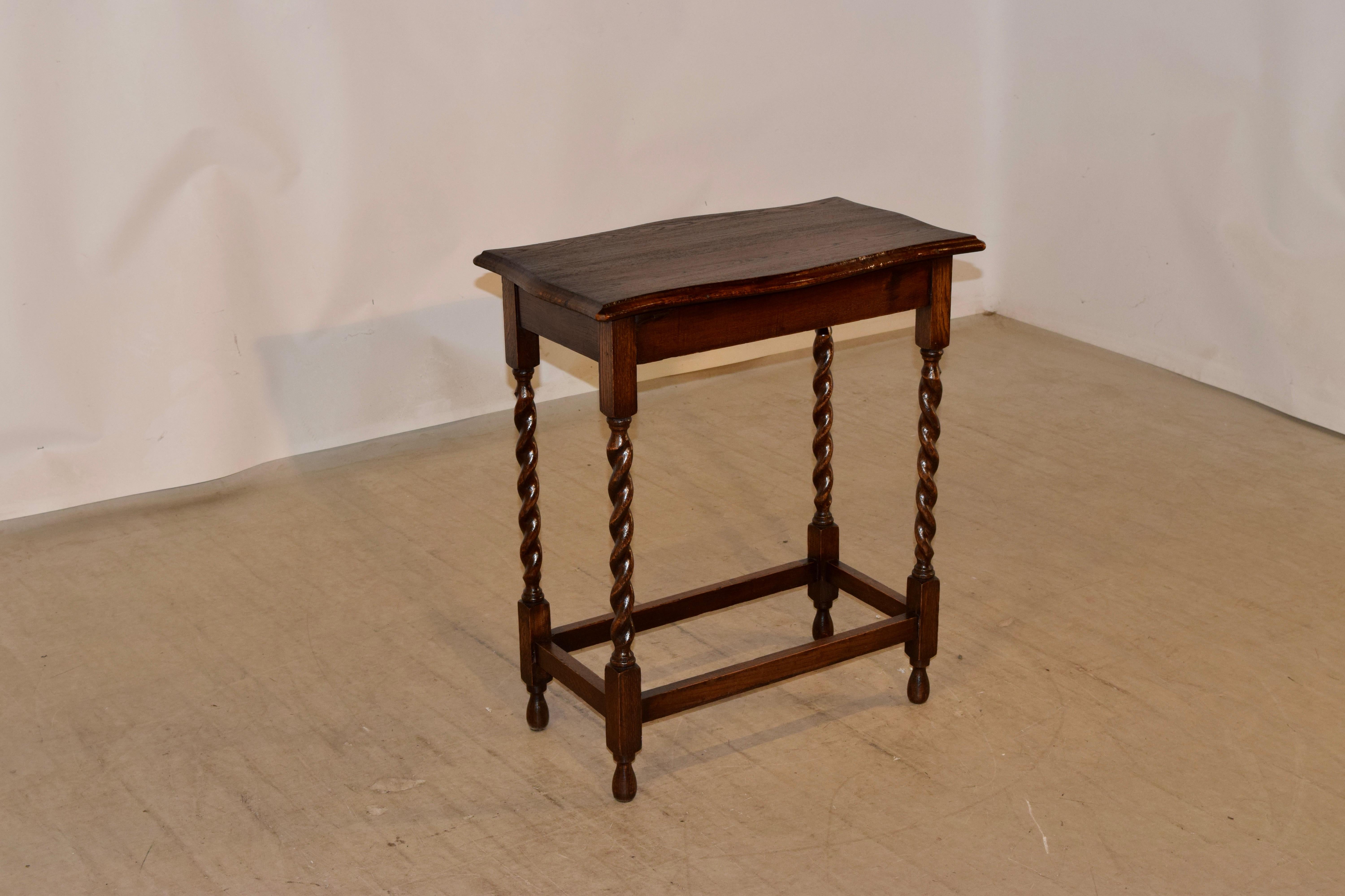 English oak occasional table, circa 1900 with a hand scalloped and beveled edge around the top, following down to a simple apron. the table is supported on hand turned barley twist legs, joined by simple stretchers and raised on hand turned feet.