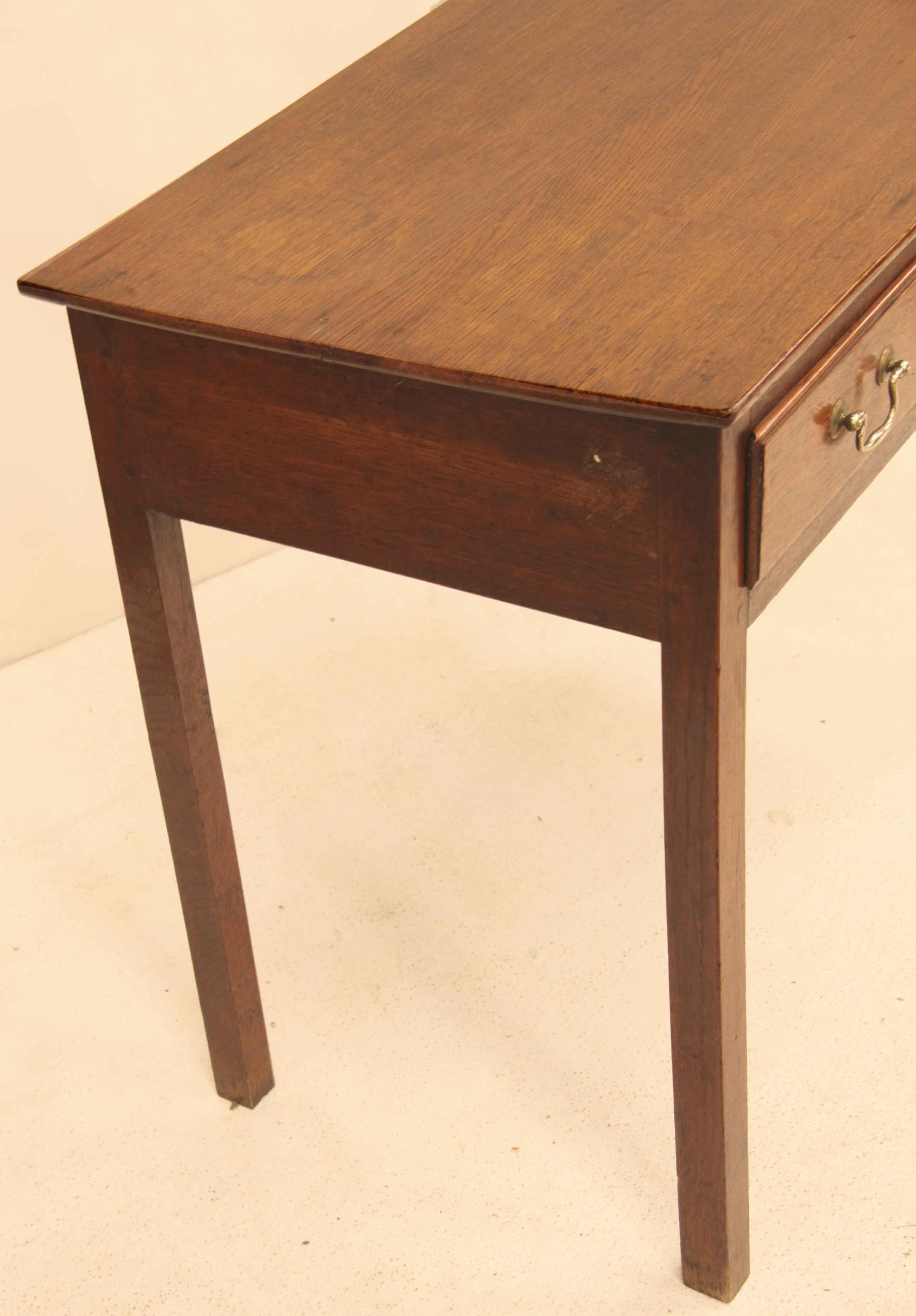 English oak one drawer side table,  the top has a straight edge around the sides and front, single drawer with overlapping molded edge, retaining the original swan neck brass pulls and escutcheon, secondary wood is oak. The straight legs are