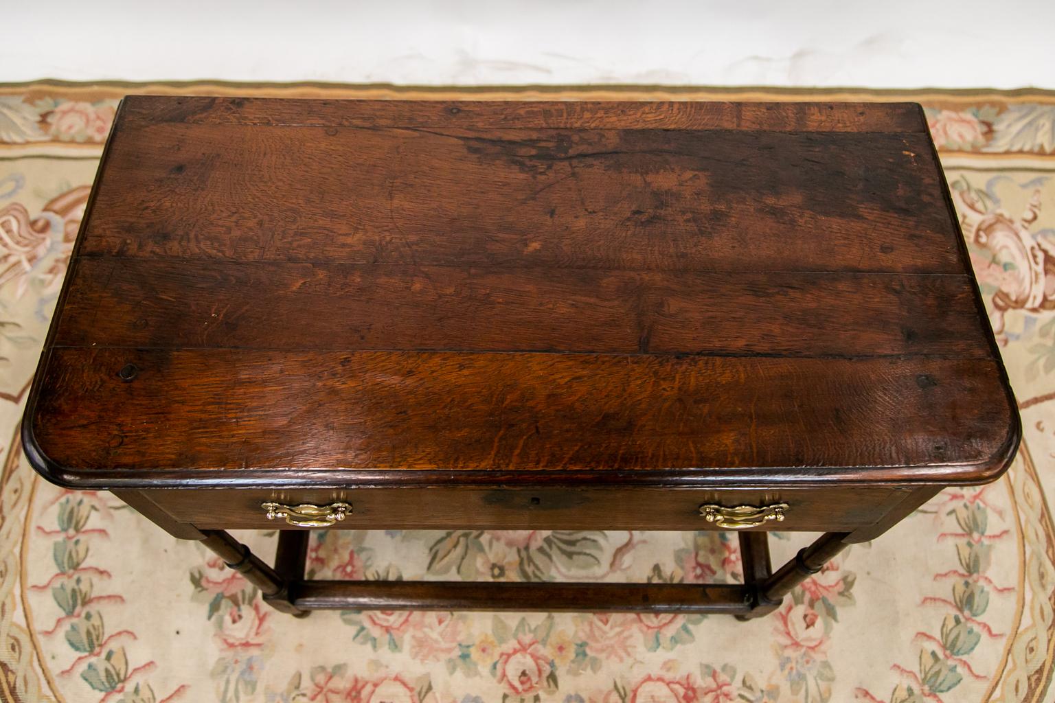 The top of this stretcher table has a molded edge and exposed peg construction. The lower edge of the apron has carved beading. The legs are turned and joined by stretchers that have a shaped molded top.