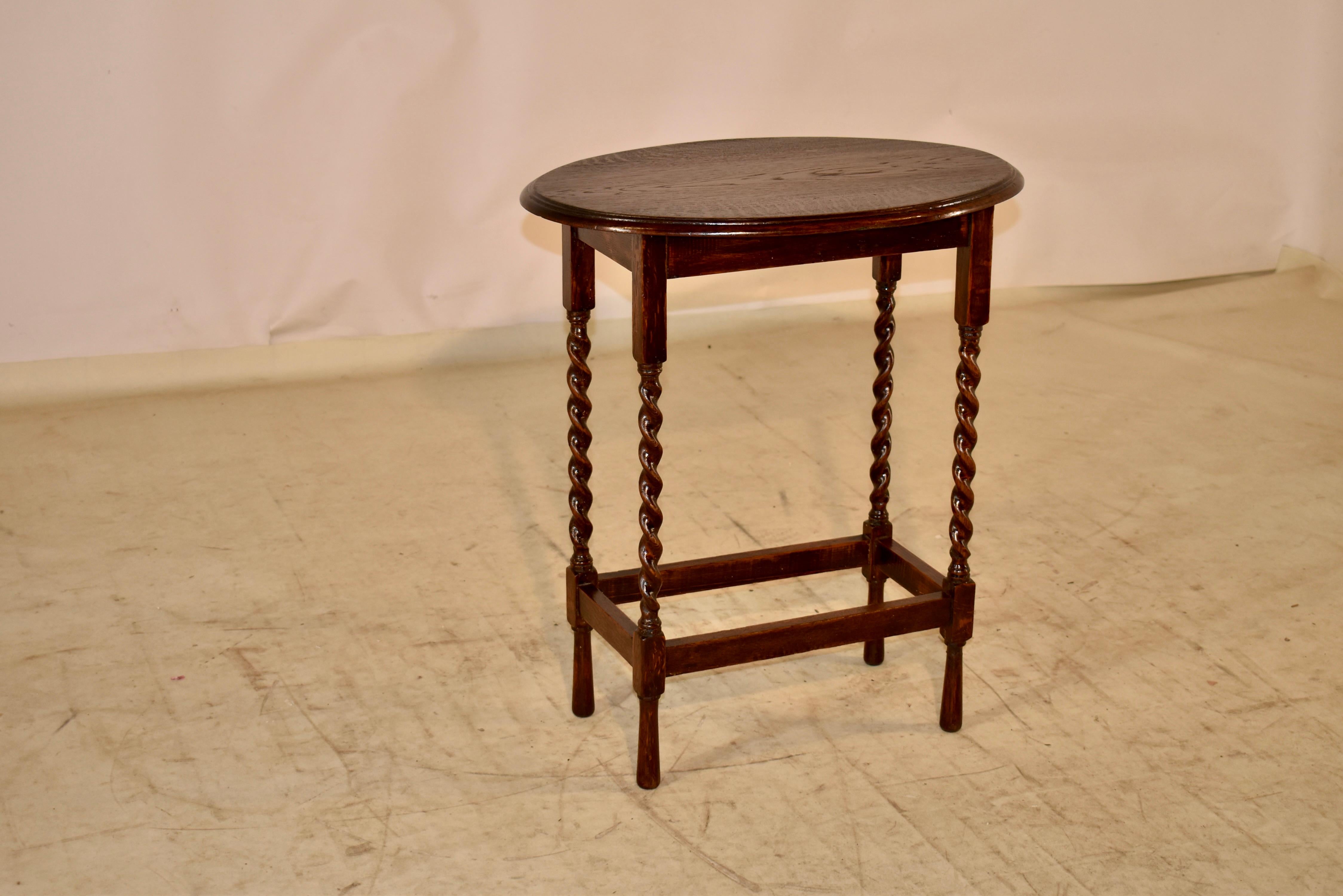 Oak side table from England with an oval top, circa 1900. The top has a beveled edge and follows down to a simple apron and is supported on hand turned barely twist legs, joined by simple stretchers and raised on hand turned feet.