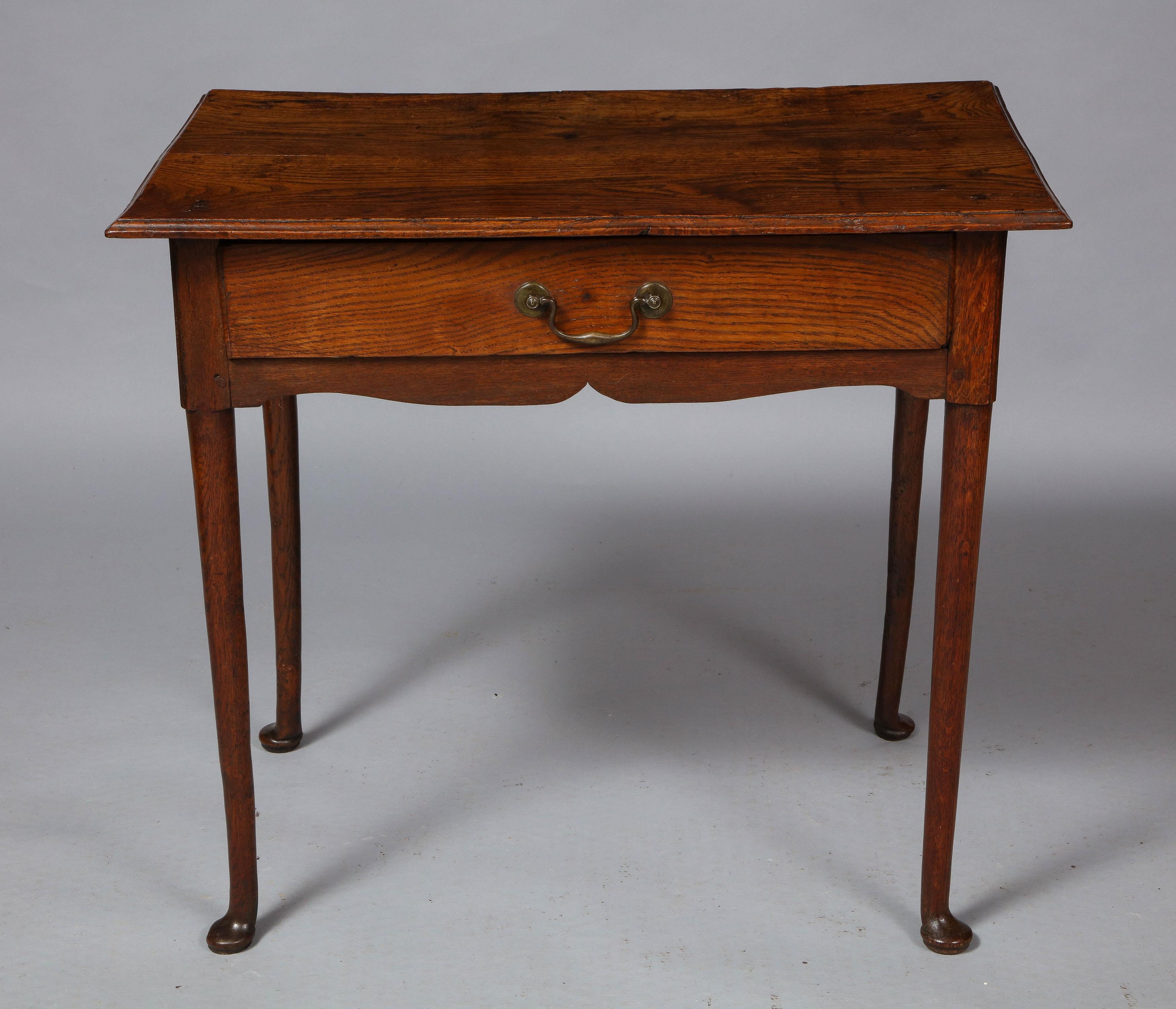 Fine 18th century English oak side table, the molded top over single drawer with brass bail handle, having gently scalloped apron, standing on turned legs ending in pad feet, the whole with good color and patina.