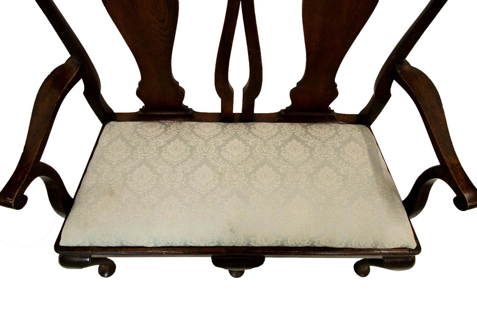 This settee has a shaped crest rail with vase back splats which are curved to make a comfortable contour for back support. The front edge has a shaped molding. The three cabriole legs in the front are interconnected with an elaborate system of