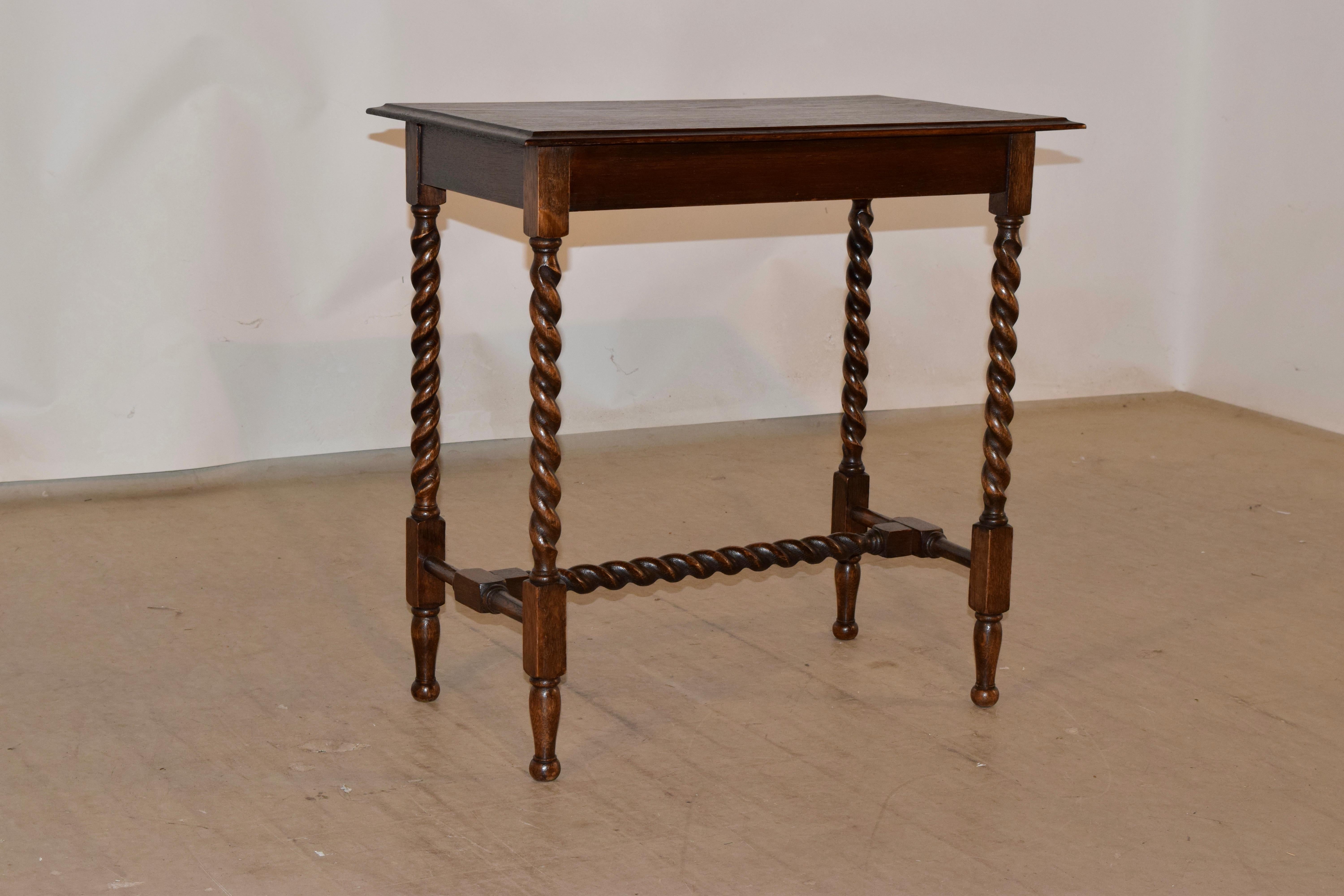 Circa 1900 oak side table from England. The top has a prominently beveled edge, following down to a simple apron and supported on hand turned barley twist legs, joined by turned stretchers and a matching barley twist cross stretcher. The feet are