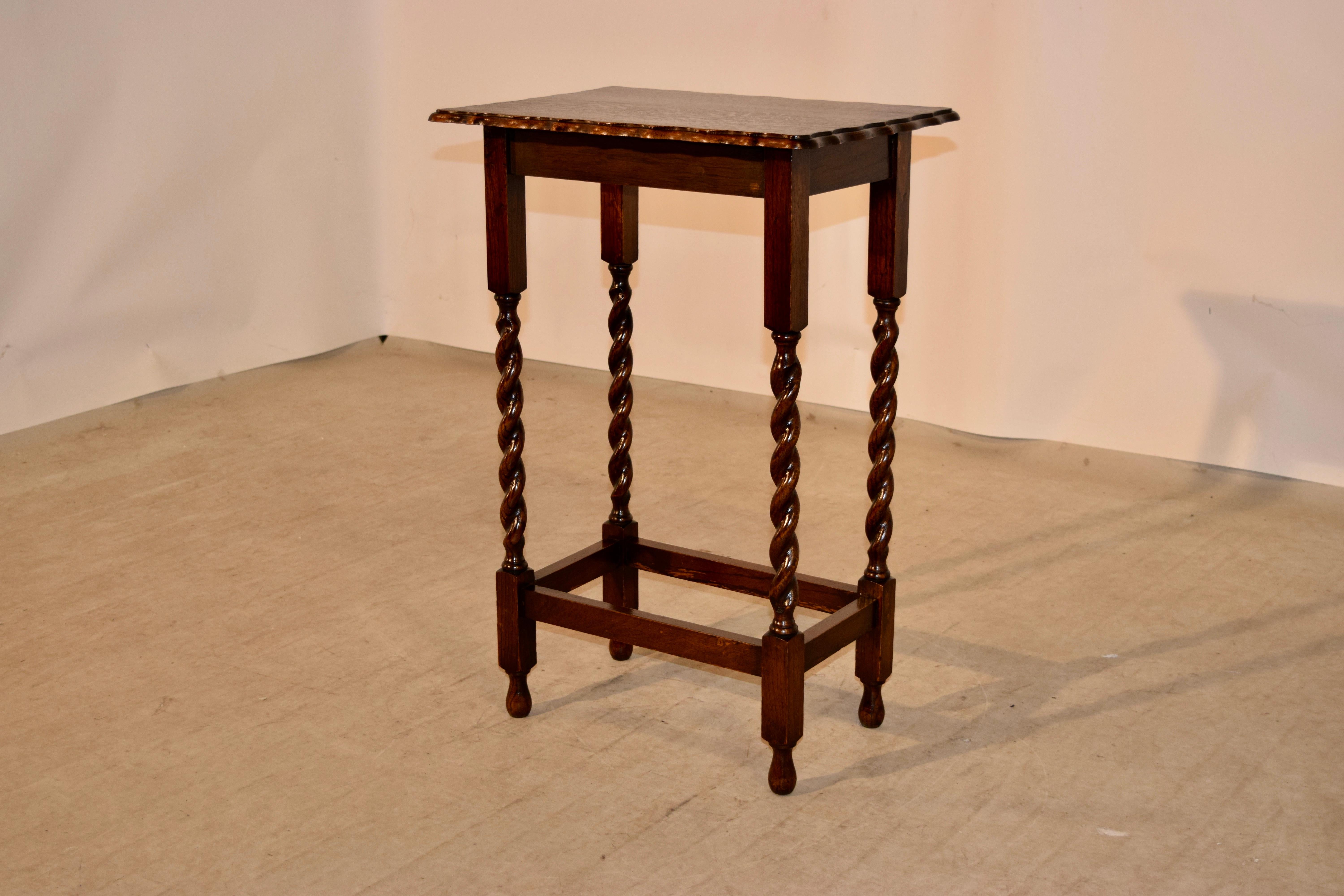 Oak side table from England with a beveled and scalloped edge around the top following down to a simple apron and supported on hand-turned barley twist legs, joined by simple stretchers and raised on turned feet.