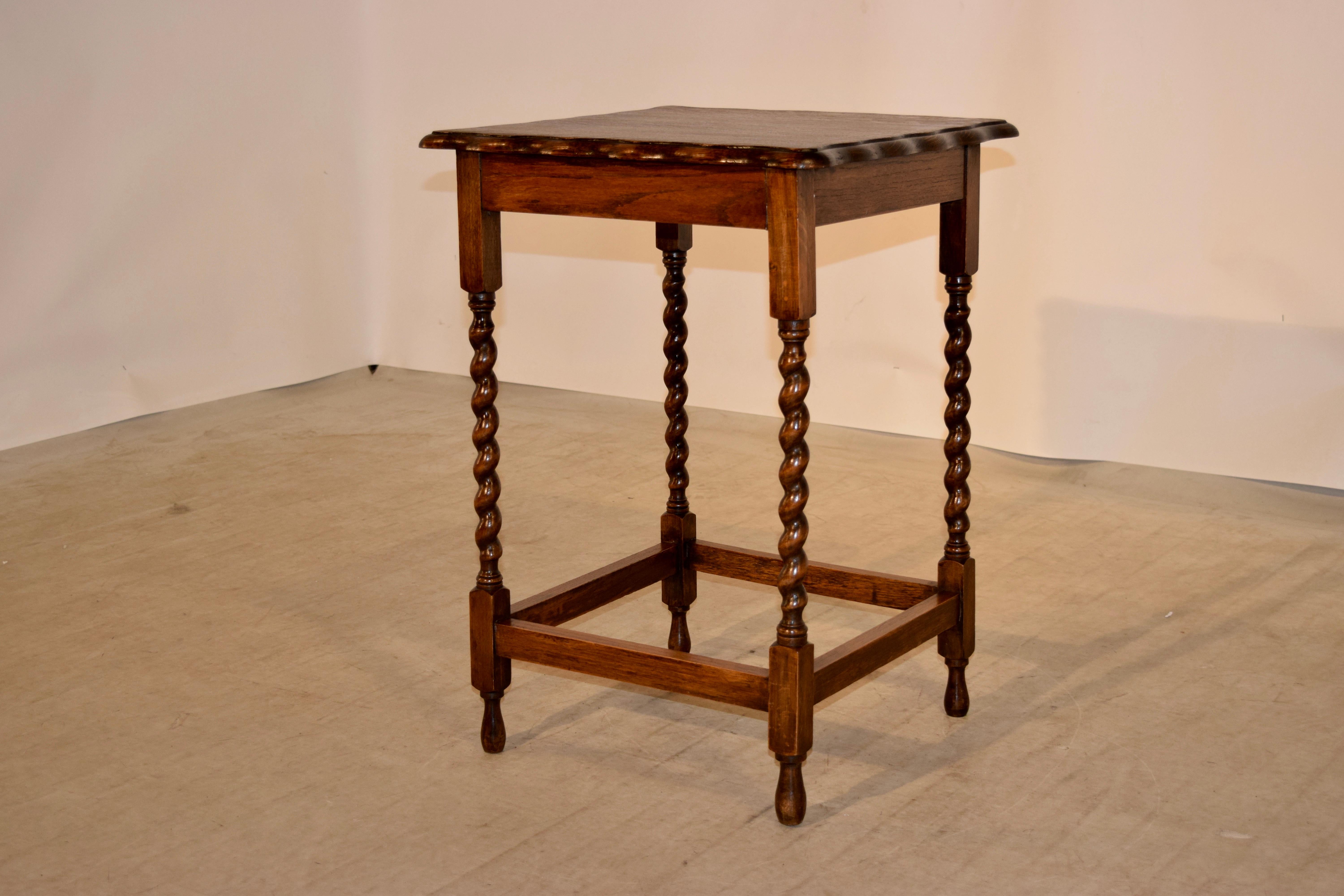 English oak side table with a scalloped and beveled edge around the top following down to a simple apron and supported on hand turned barley twist legs joined by stretchers and raised on hand turned feet, circa 1900.