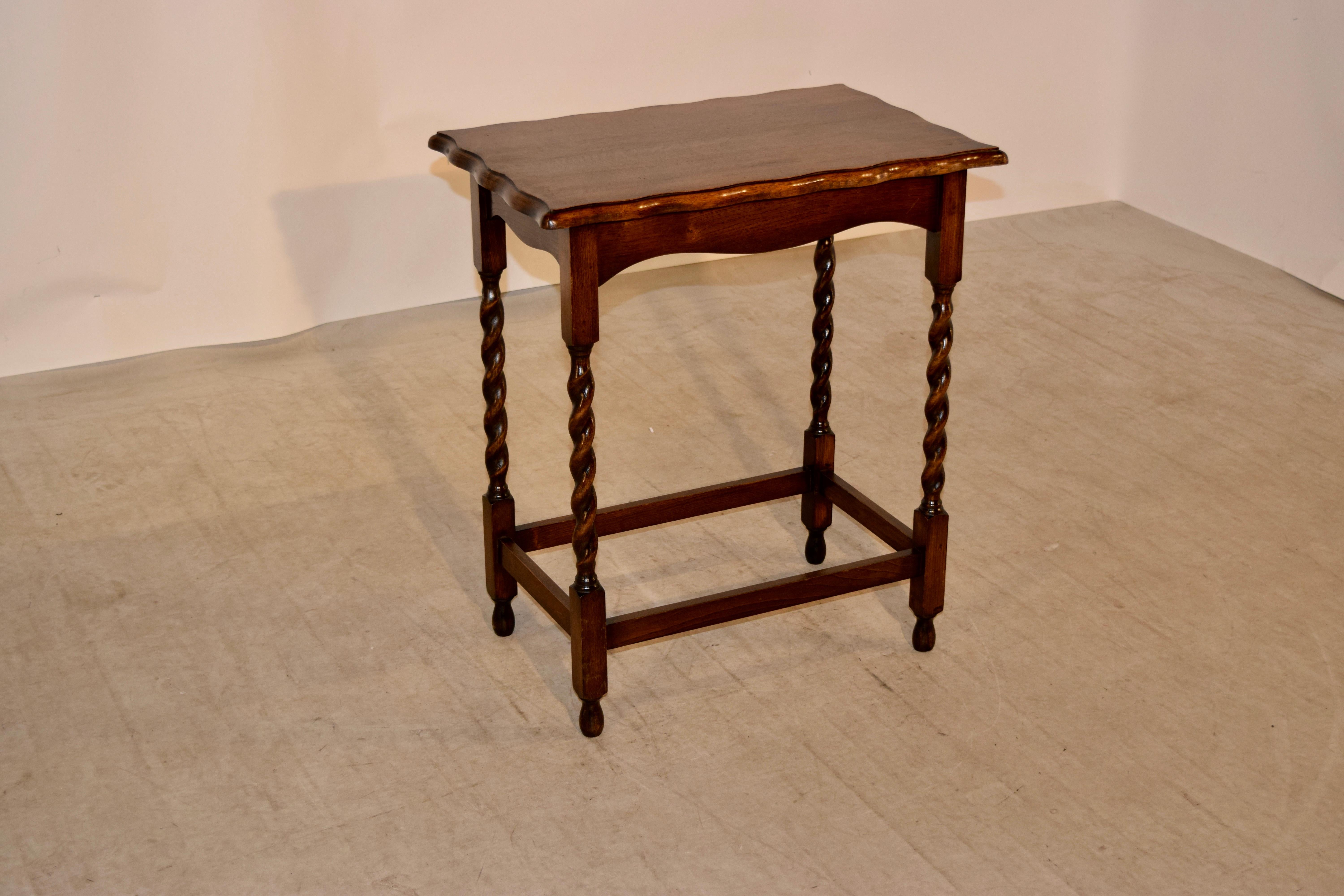 English oak side table with a scalloped and beveled edge around the top and a simple apron, supported on hand turned barley twist legs joined by simple stretchers and raised on turned feet, circa 1900.
