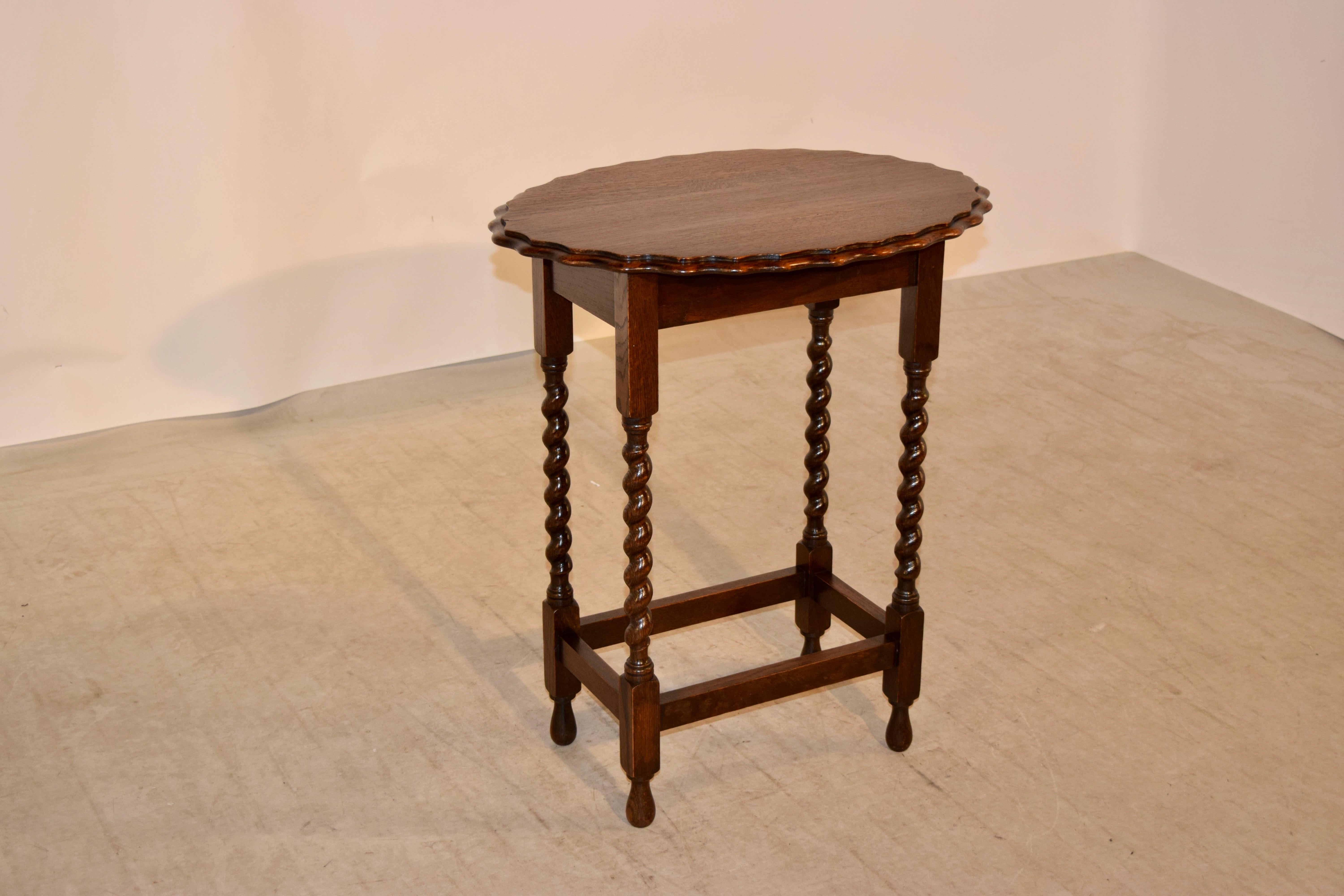 English oak side table with an oval shaped top with a beveled and scalloped edge, following down to a simple apron and supported on hand turned barley twist legs joined by stretchers and raised on hand turned feet, circa 1900.