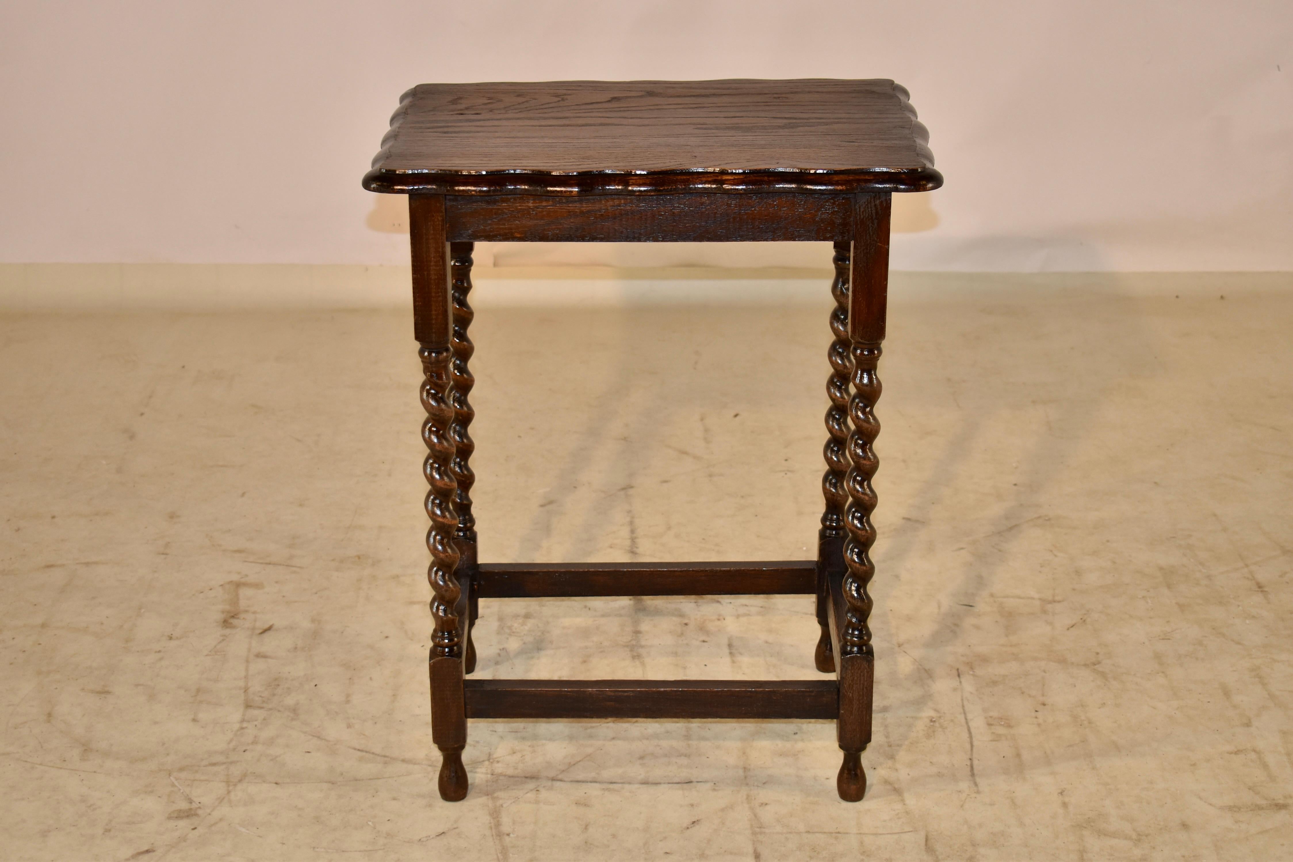circa 1900 English oak side table with a beveled and scalloped edge around the top, following down to a simple apron and supported on hand turned barley twist legs, joined by simple stretchers and supported on hand turned feet.