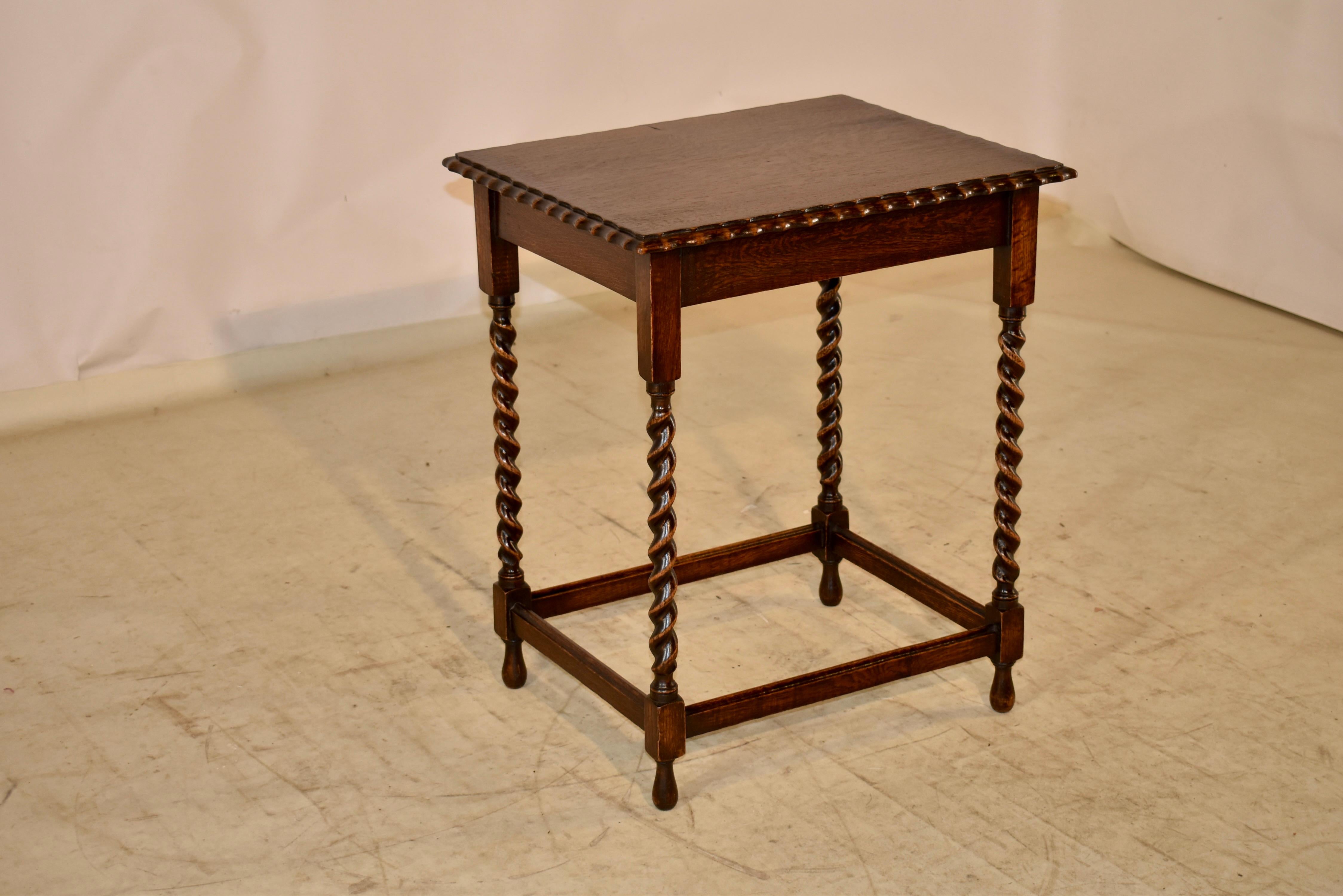 Circa 1900 oak side table from England. The top is nicely grained and has a beveled and scalloped edge, following down to a simple apron. The table is raised on hand turned barley twist legs, joined by simple stretchers and supported on hand turned