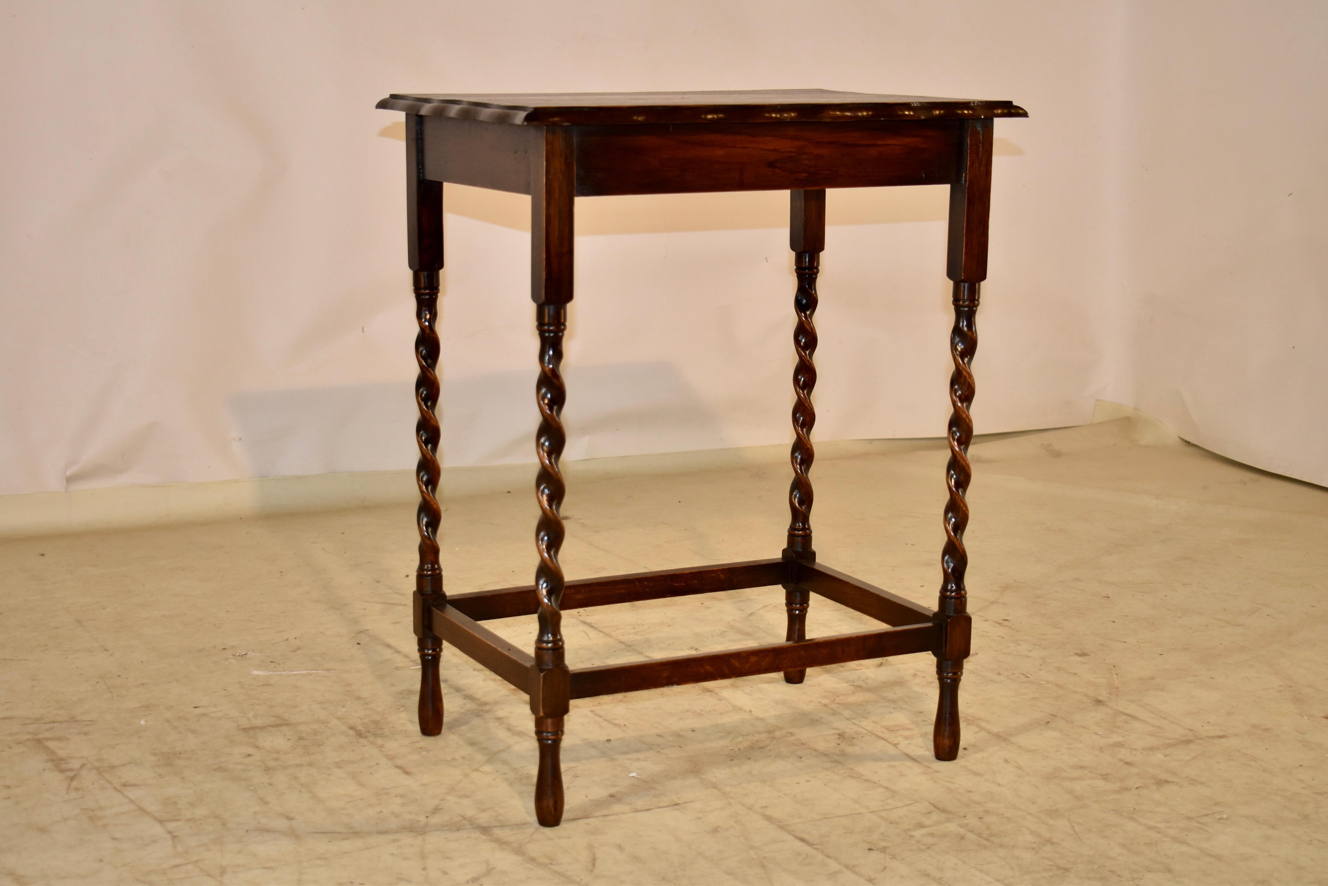 Circa 1900 English oak side table with a beveled and scalloped edge around the top, following down to a simple apron.  the table is supported on hand turned barley twist legs, joined by simple stretchers.  Raised on turned feet.