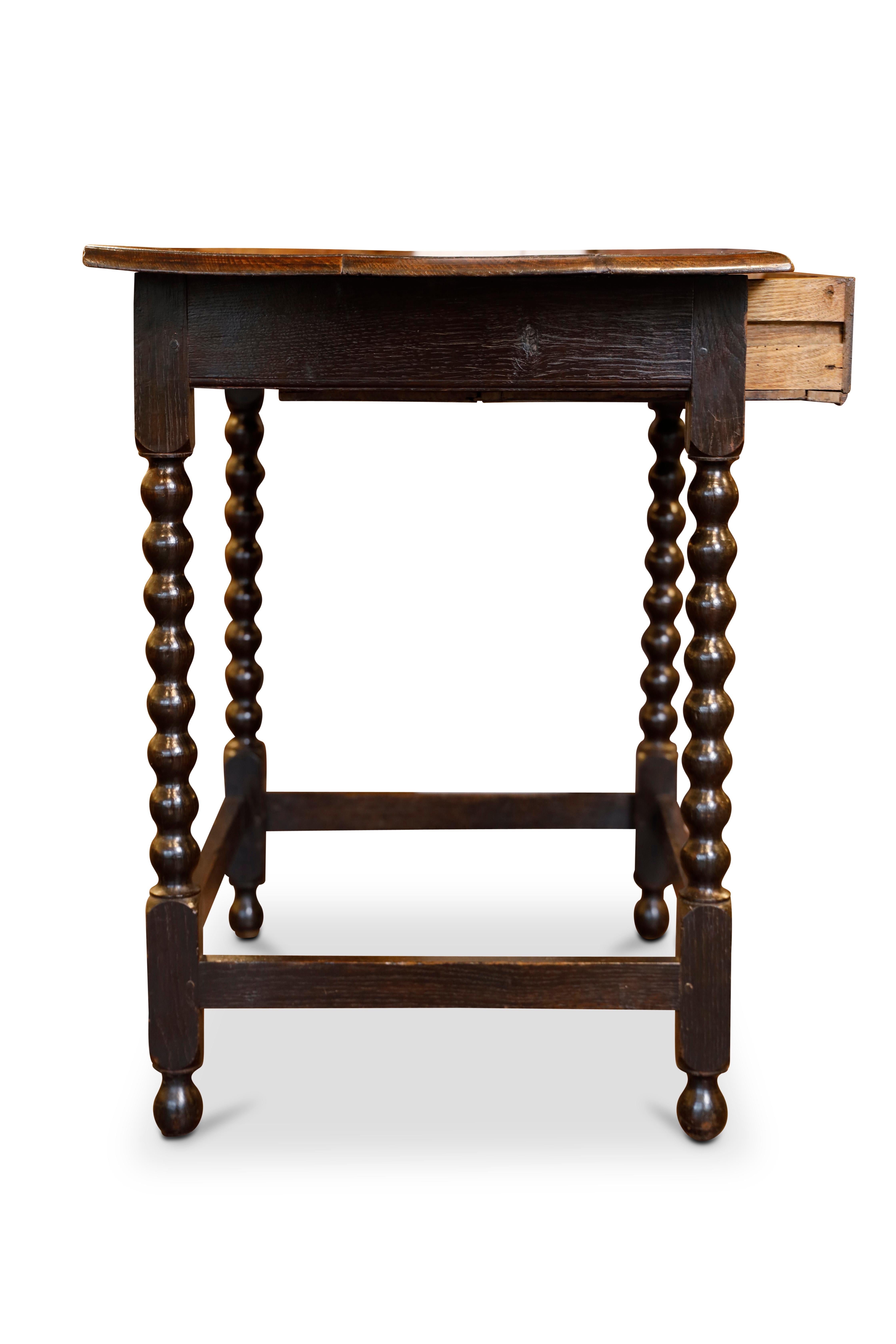 Mesa victoriana de roble con tablero sobrepuesto sobre un cajón de un friso con tiradores originales de latón.  Patas torneadas unidas por una camilla.
