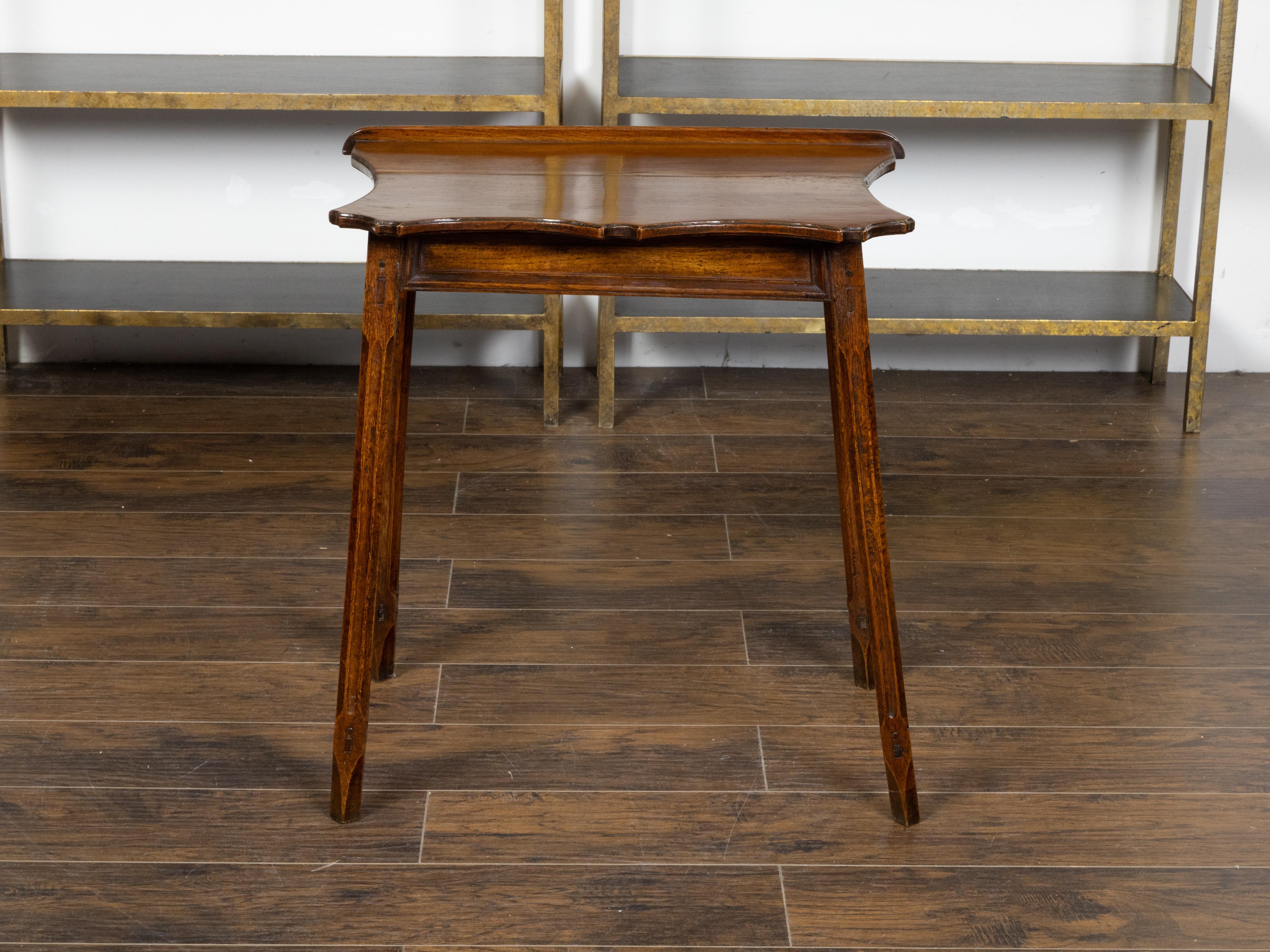 An English carved oak side table from the 19th century, with lift top, serpentine front, slender fluted legs, weathered appearance and peg construction. Created in England during the 19th century, this small oak side table charms us with its