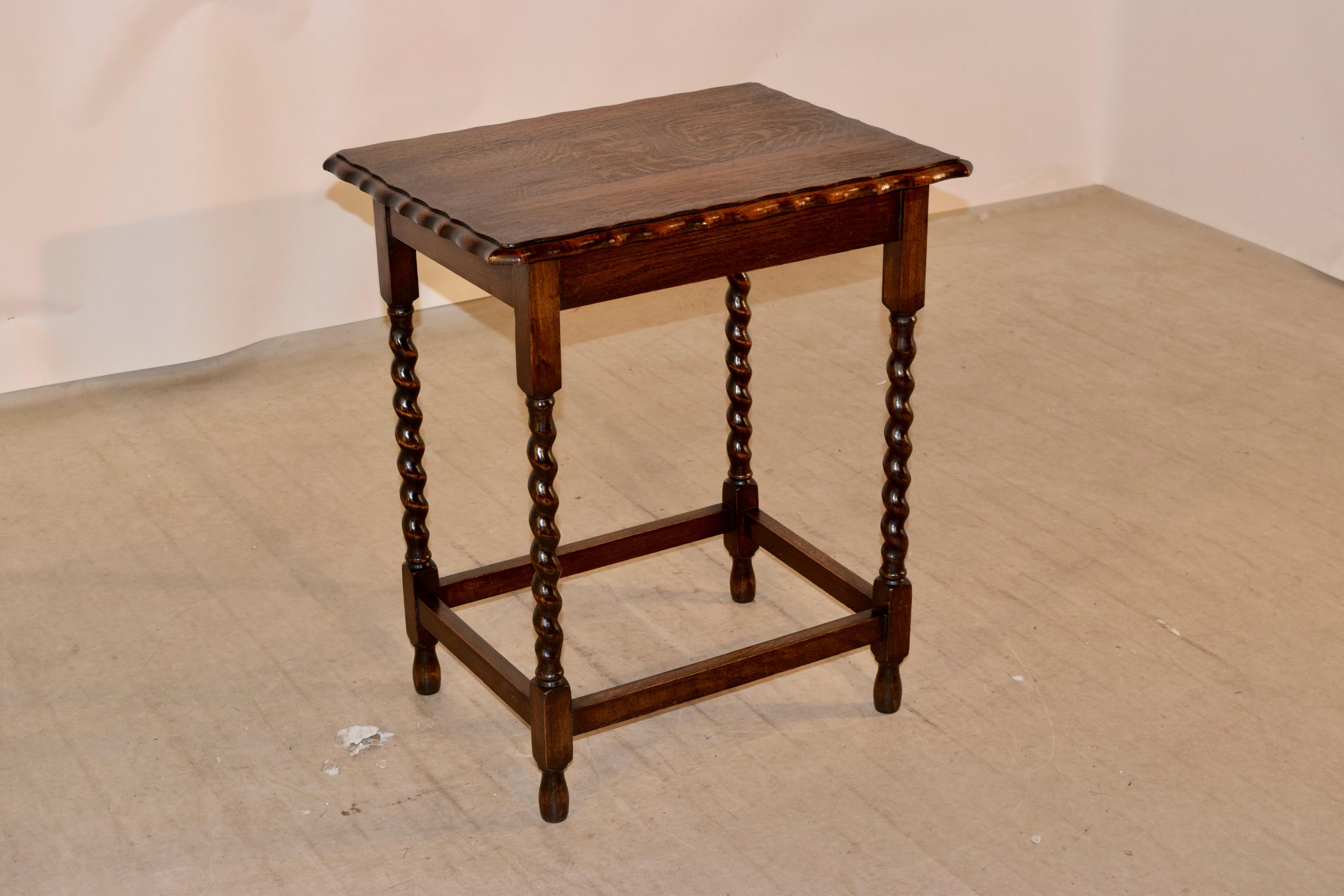 Oak side table from England with a scalloped and bevelled edge around the top following down to a simple apron and supported on hand turned barley twist legs, joined by simple stretchers and raised on hand turned feet.
