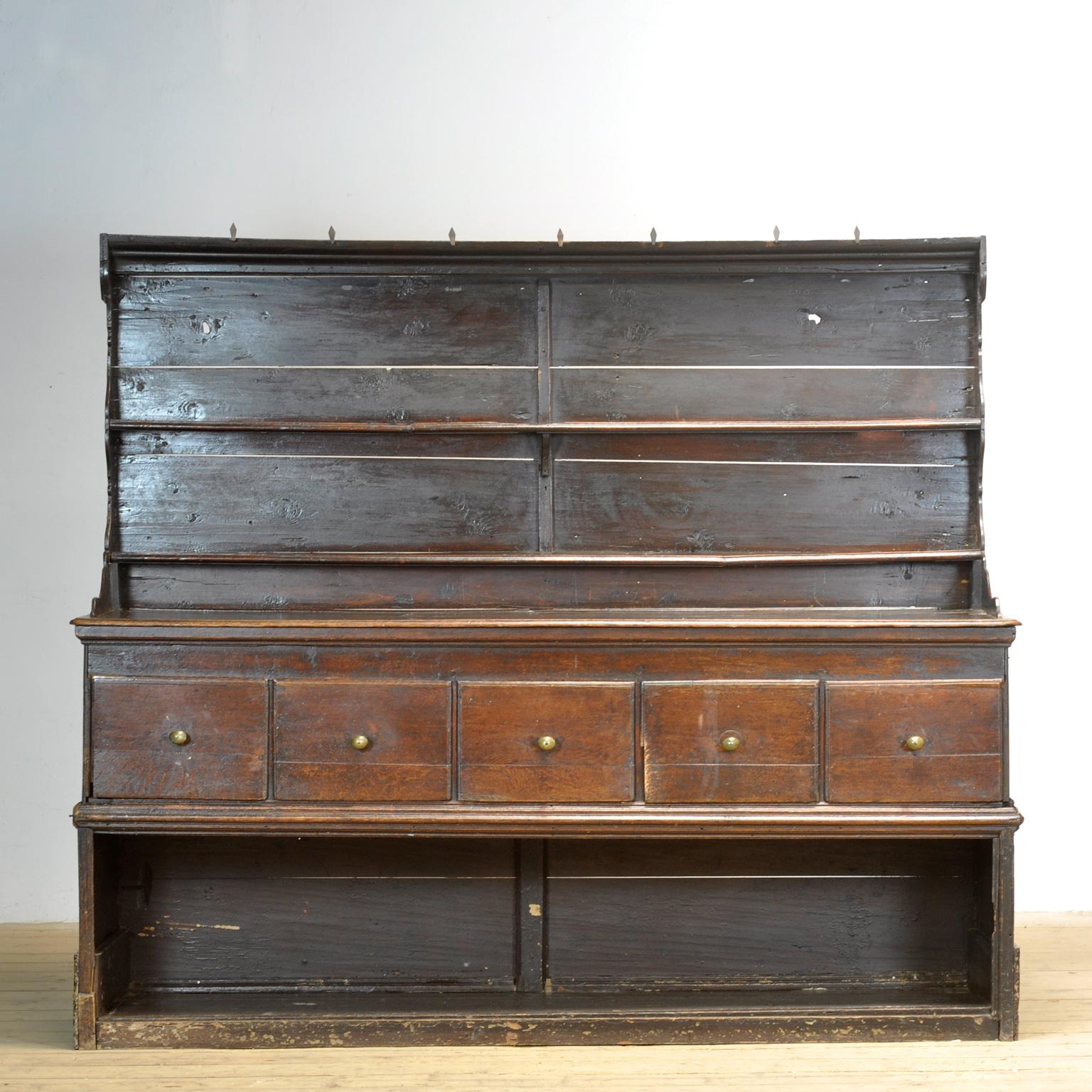 Una credenza inglese degli inizi del XVIII secolo con una spettacolare patina e un colore oro ricco. Il mobile presenta le maniglie originali in ottone sui cassetti e ganci per appendere in ferro sulla parte superiore. Un mobile ben proporzionato,