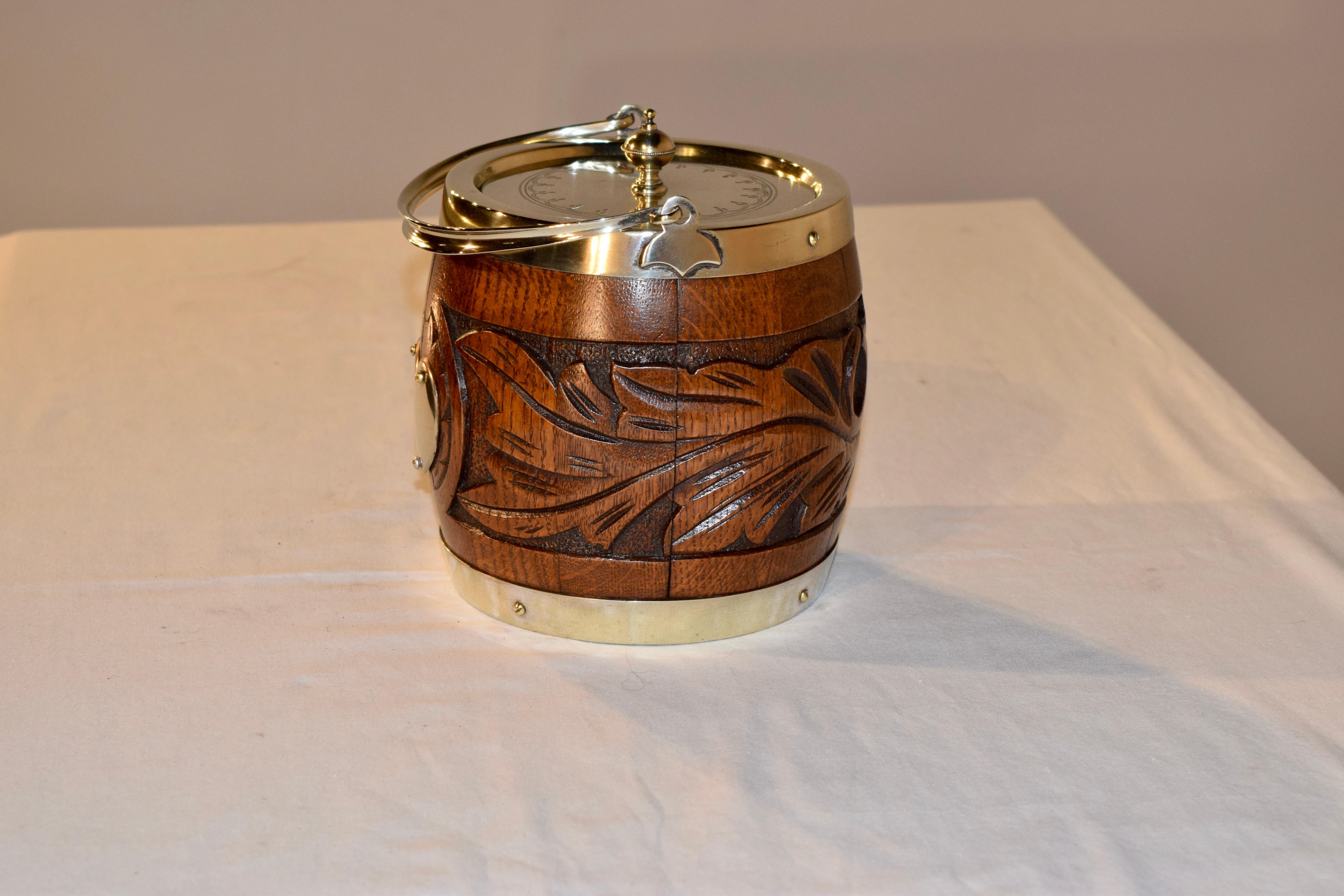 English oak biscuit barrel with the original porcelain liner and silver plated mounts and a heart shaped plaque on the front of the barrel in the center of an intricate hand carved design, circa 1900-1920. The mark is for Hammond, Creake and Co.,