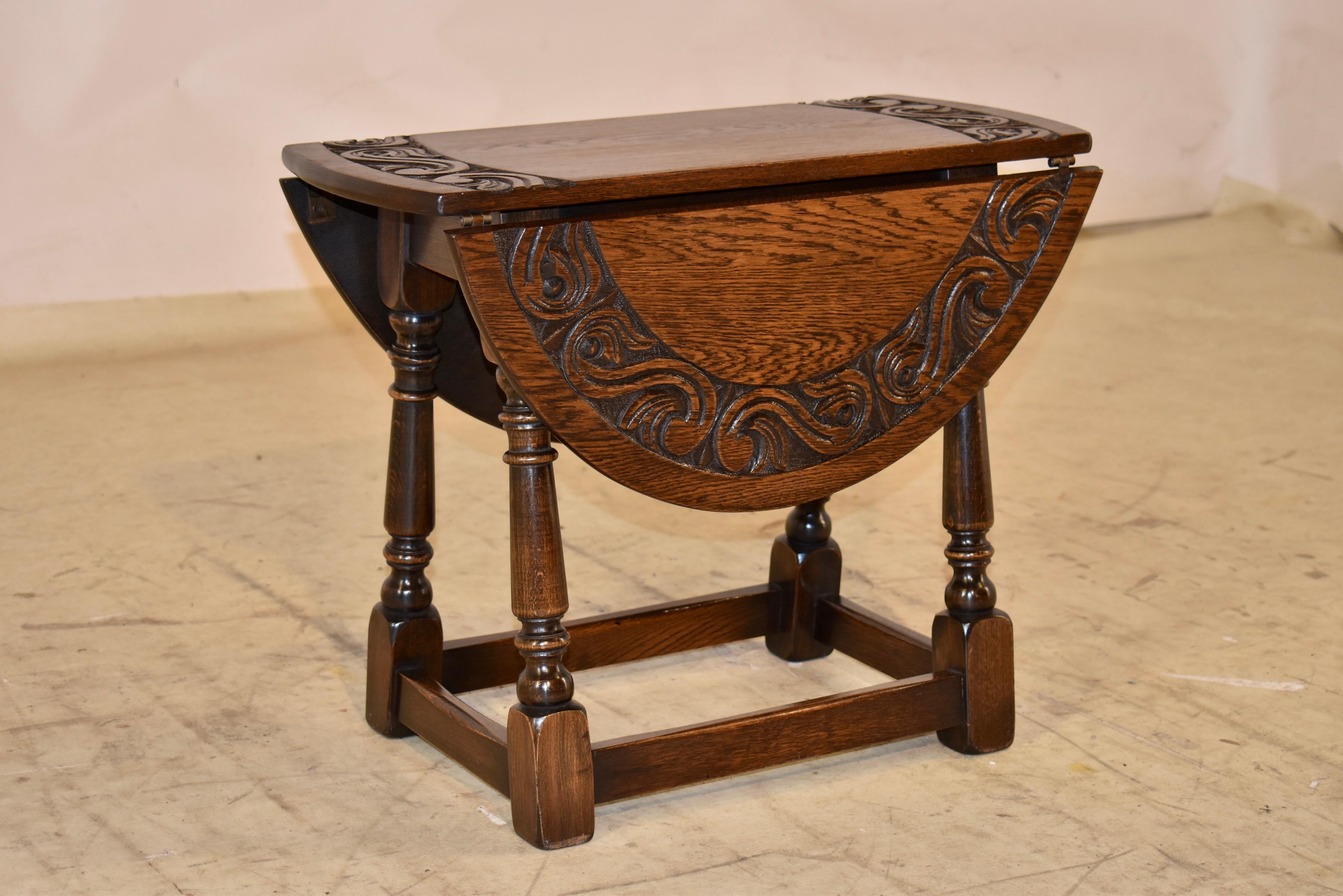 Circa 1900 period Edwardian small table with drop leaves.  The top has a hand carved band surrounding a simple center with lovely graining.  To extend the leaves, you have to lift them and turn the top.  It then forms an oval top table, and the top