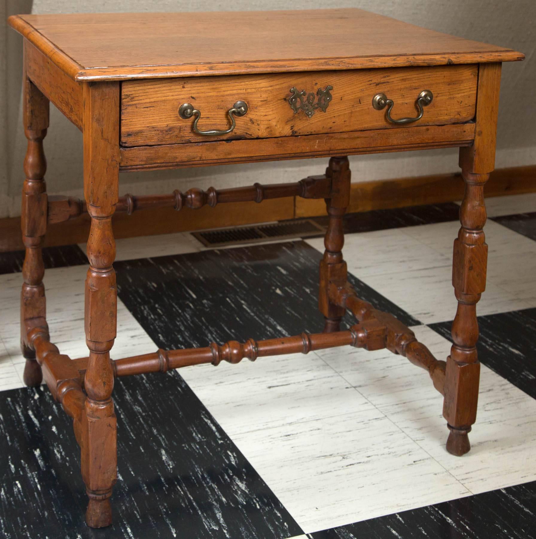 Oak tavern table with single drawer standing on turned legs and stretchers.